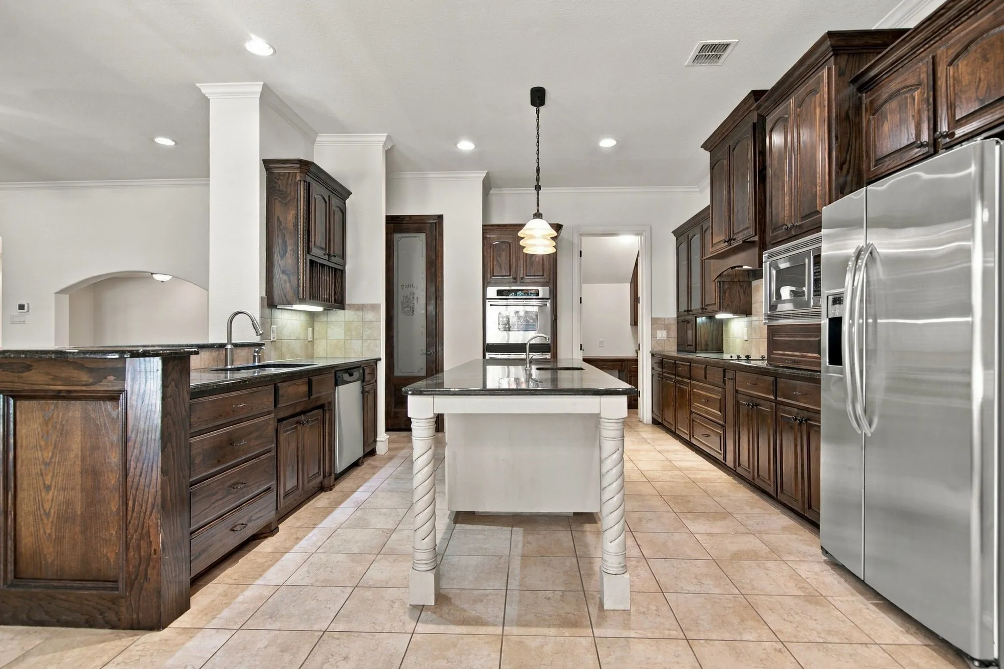 Kitchen featuring dark wood cabinetry, stainless steel appliances, a center island with decorative legs, and tile flooring