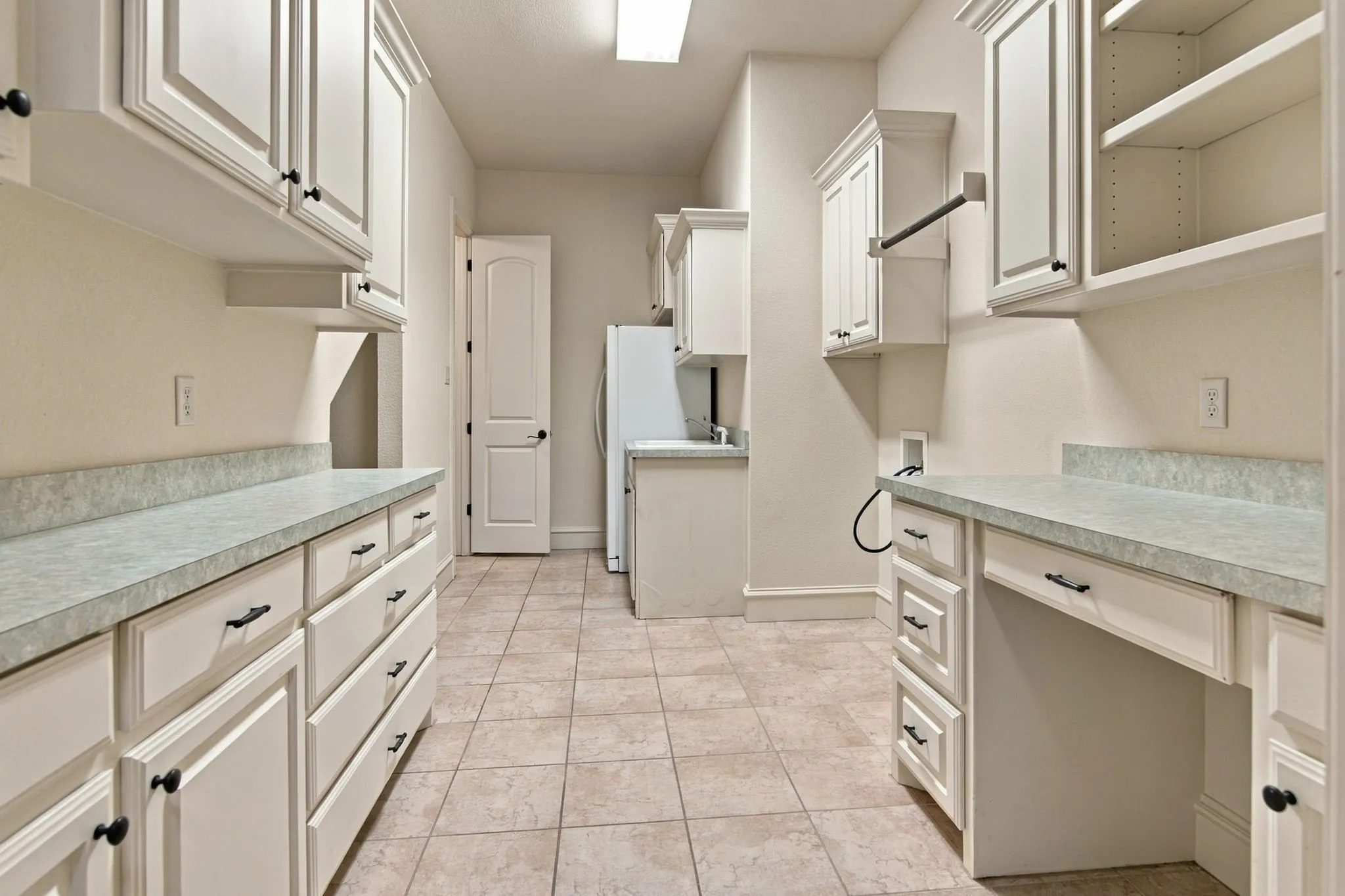 Spacious utility room featuring extensive built-in cabinetry, durable countertops, tiled flooring, and an integrated drying rack