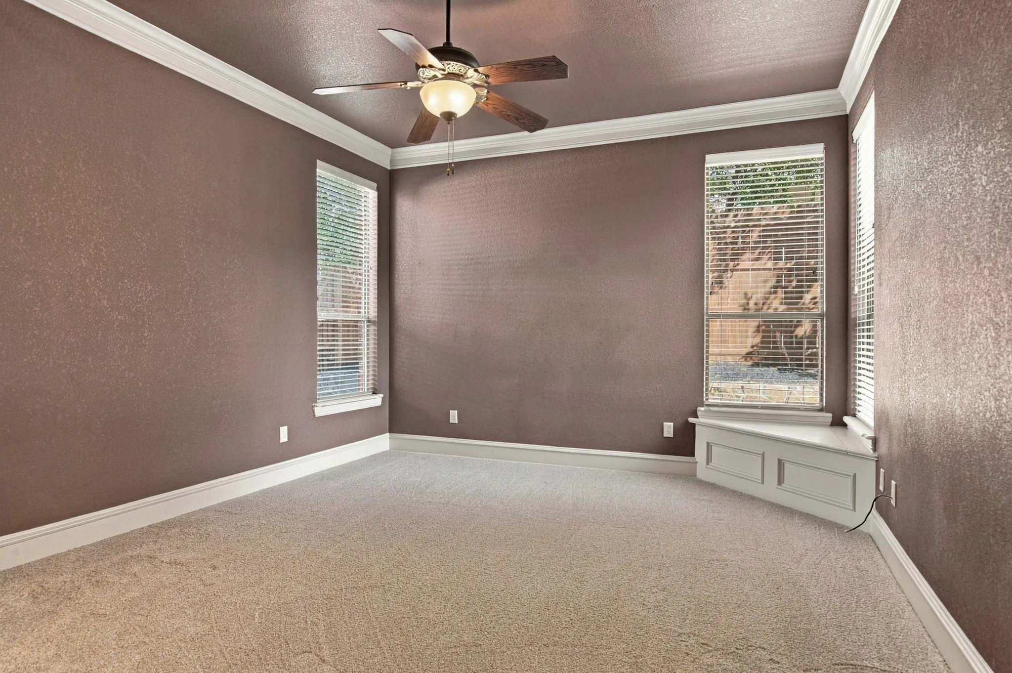 Crown molding, ceiling fan, carpeting, multiple windows, built-in window bench
