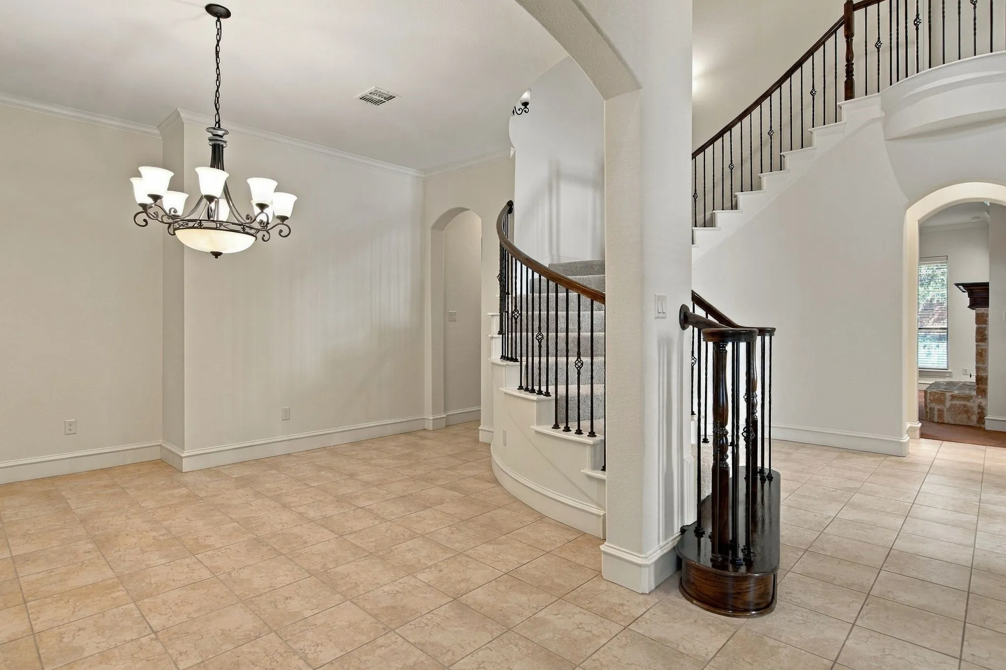Grand curved staircase with wrought iron balusters and wood handrail