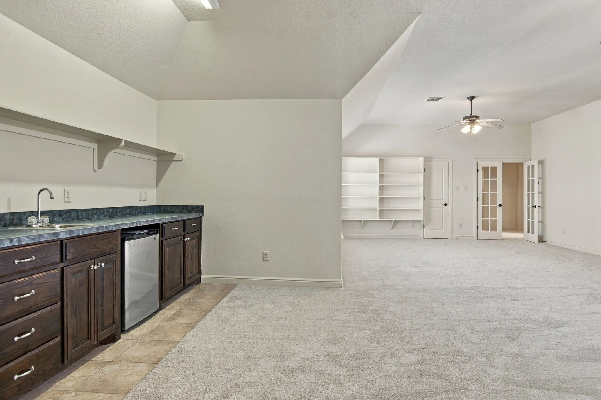 Built-in wet bar with wood cabinetry, integrated mini-refrigerator, and wall-mounted shelving