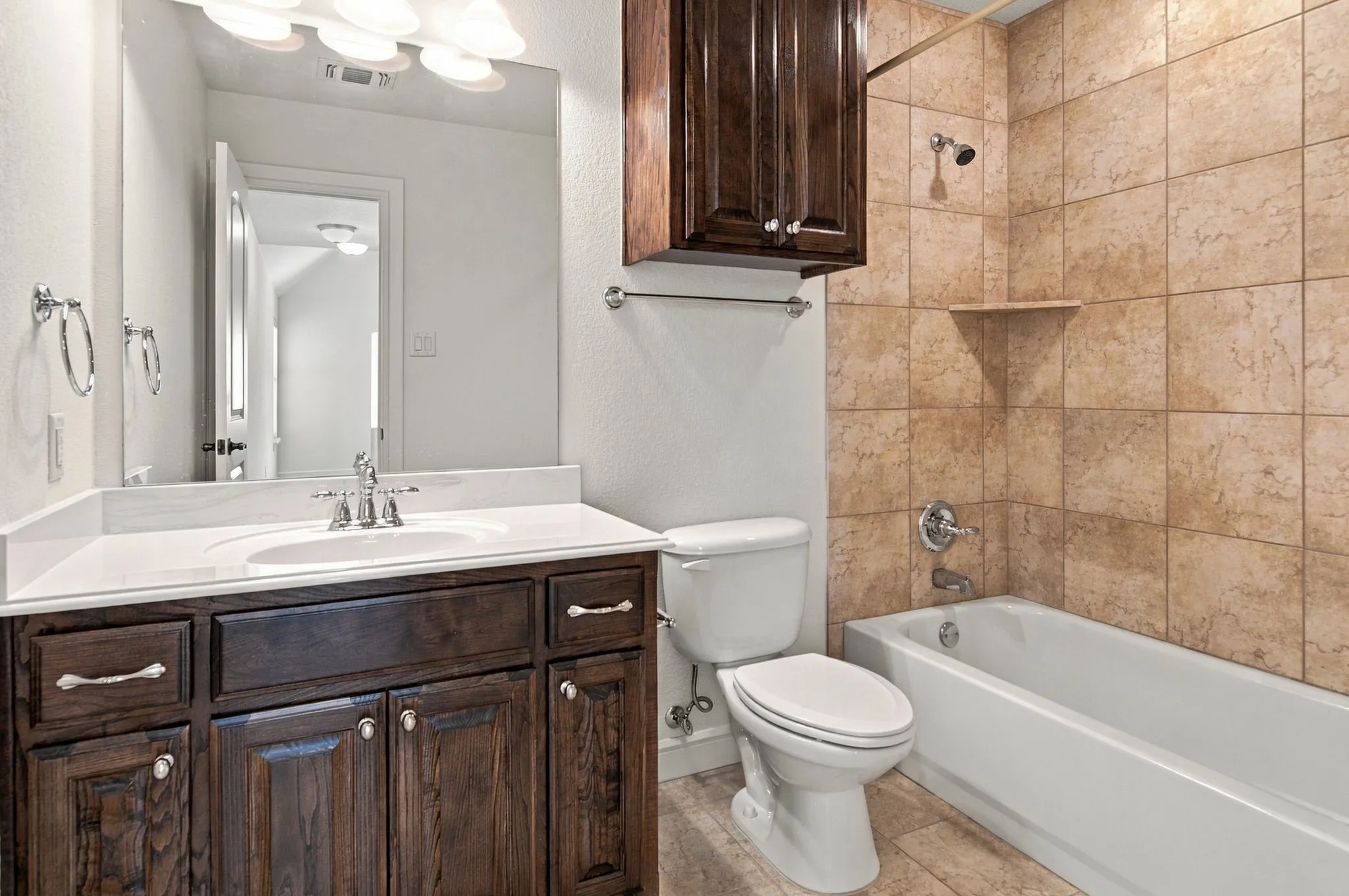Dark wood-finish vanity with white countertop, chrome fixtures, and overhead light bar