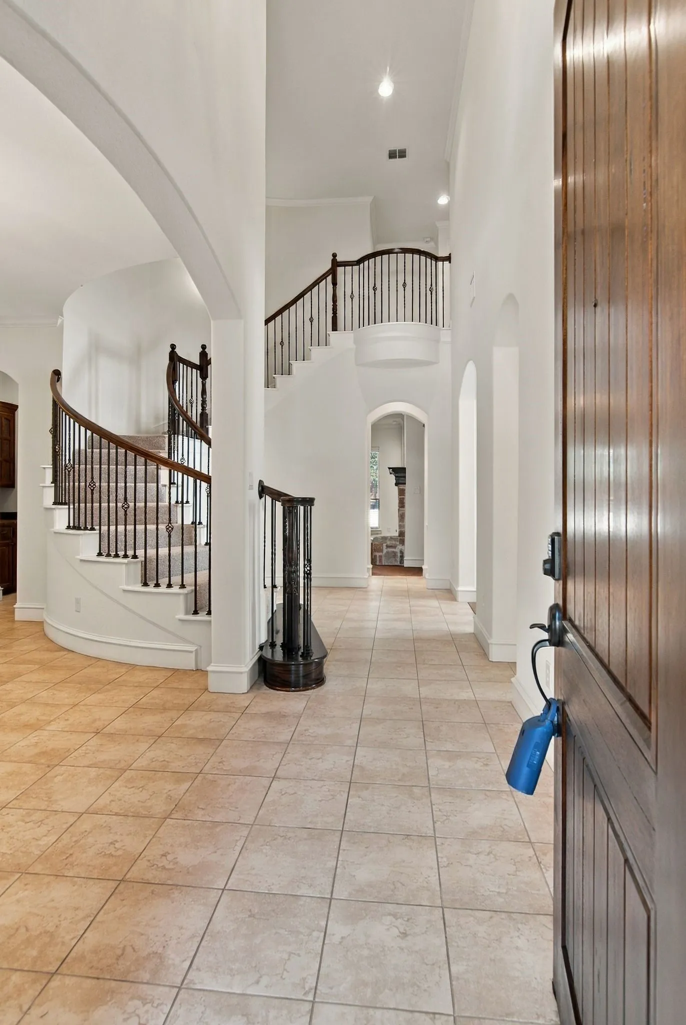 Grand entry featuring a curved staircase with wrought iron balusters, high ceilings, recessed lighting, and tile flooring