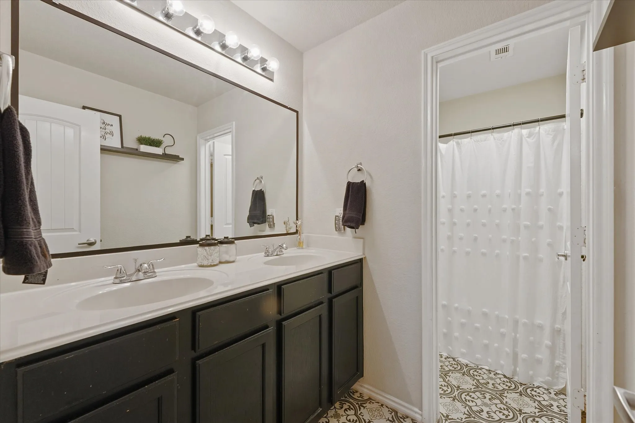 Dual vanity with undermount sinks, stone-look countertop, and dark cabinetry