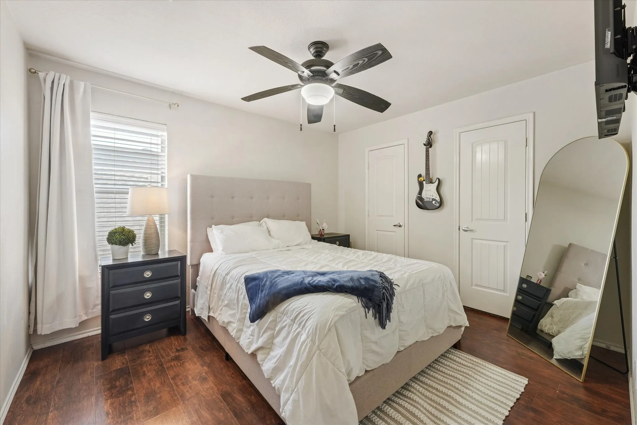 Wood-finish flooring with white walls and a ceiling fan with integrated lighting