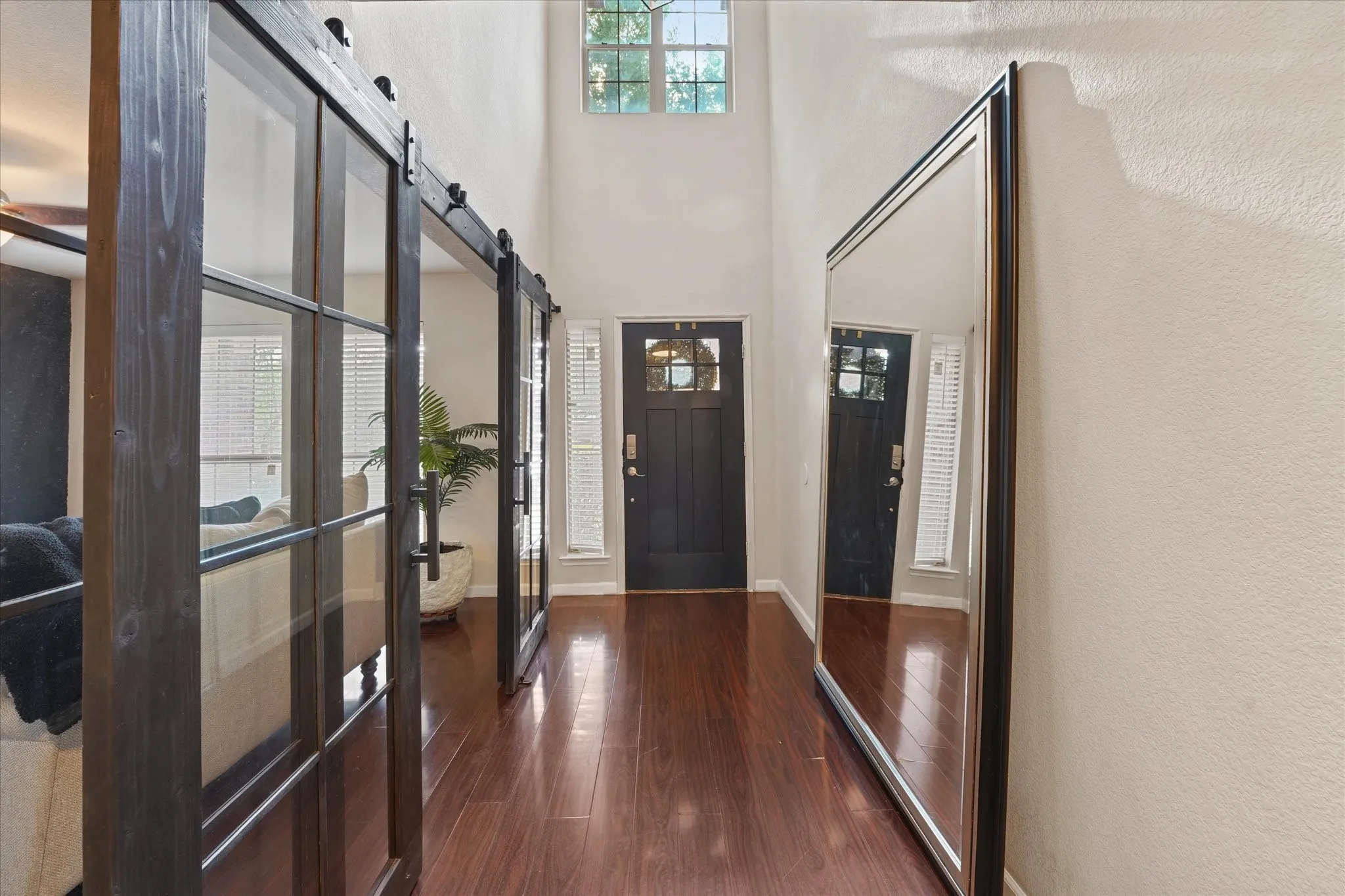 Hardwood-style flooring, high vaulted ceilings, transom window, and paneled barn doors with glass inserts