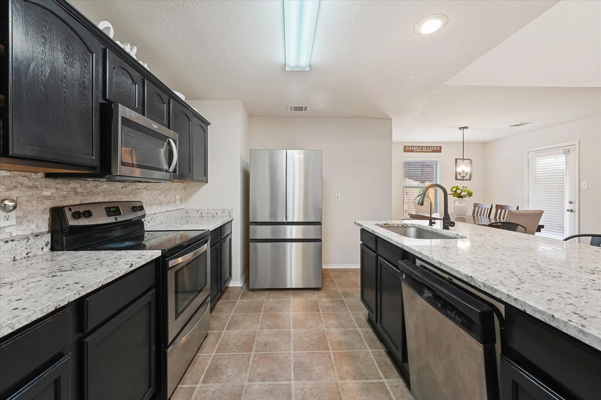 Kitchen featuring dark cabinetry, light-colored countertops, stainless steel appliances, and tile flooring