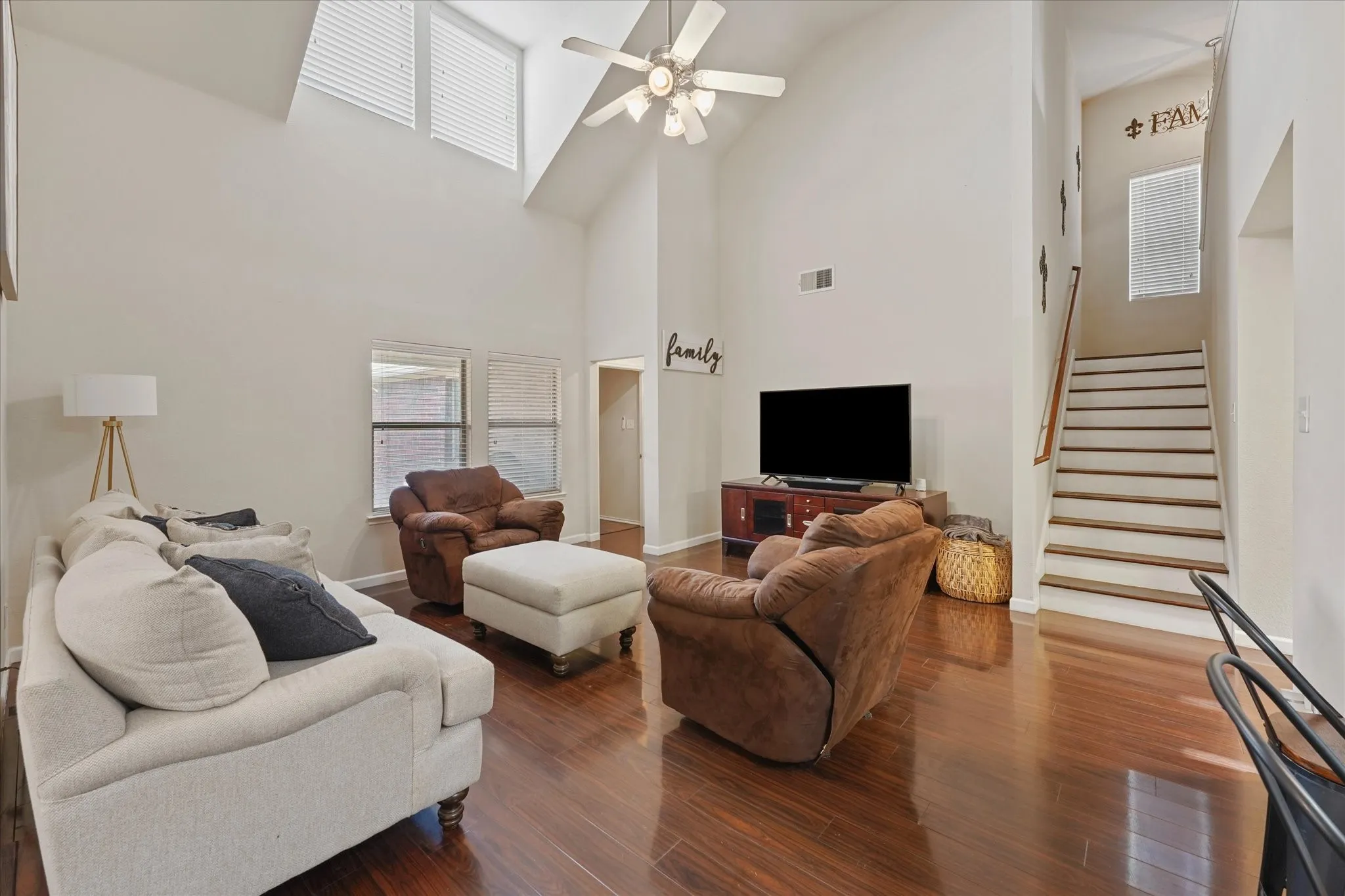 Vaulted ceiling with a ceiling fan, recessed windows, wood-finish flooring, and a staircase with wood treads