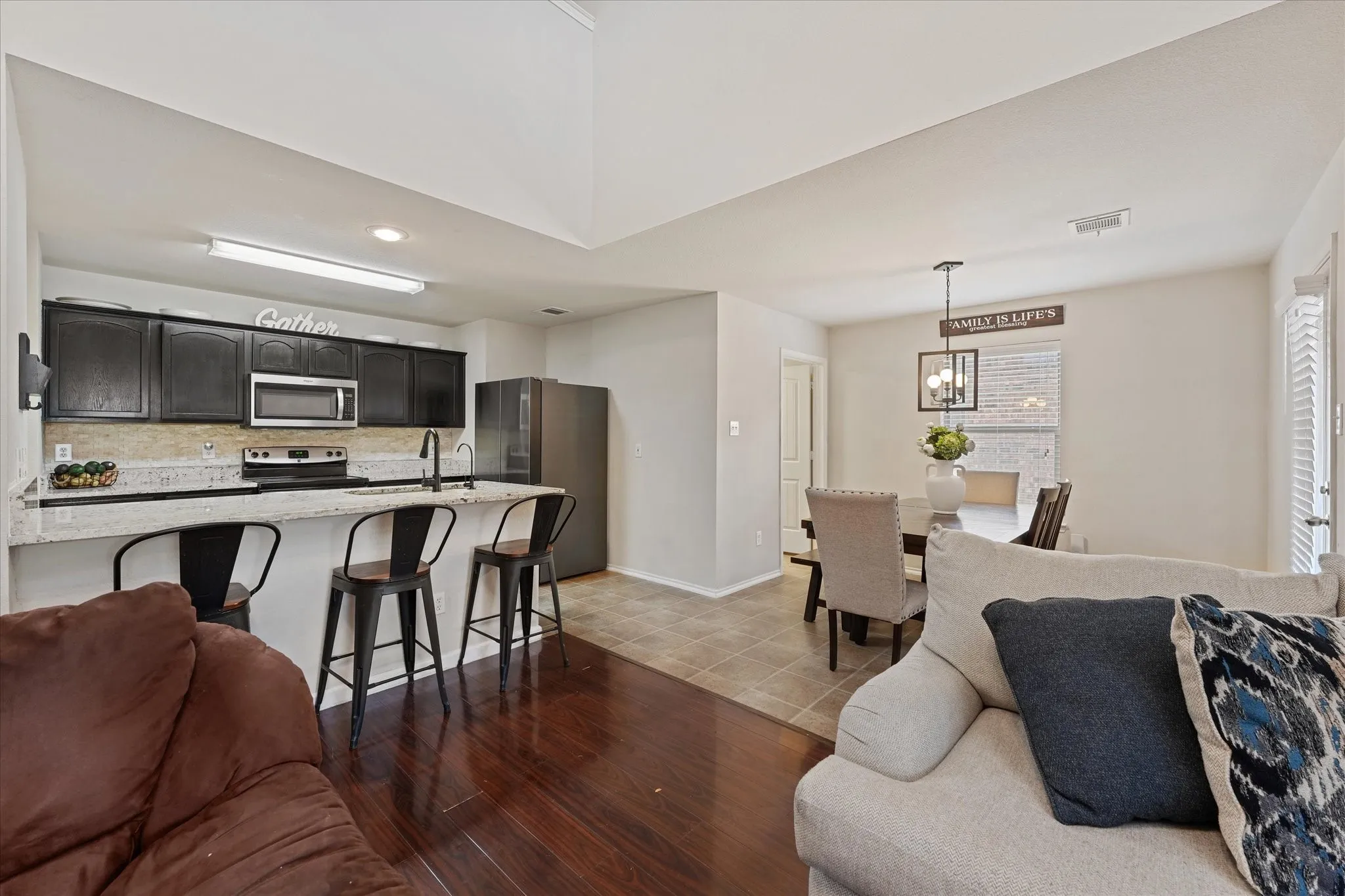 Kitchen featuring dark wood cabinetry, stainless steel appliances, and a breakfast bar with stone-finish countertop