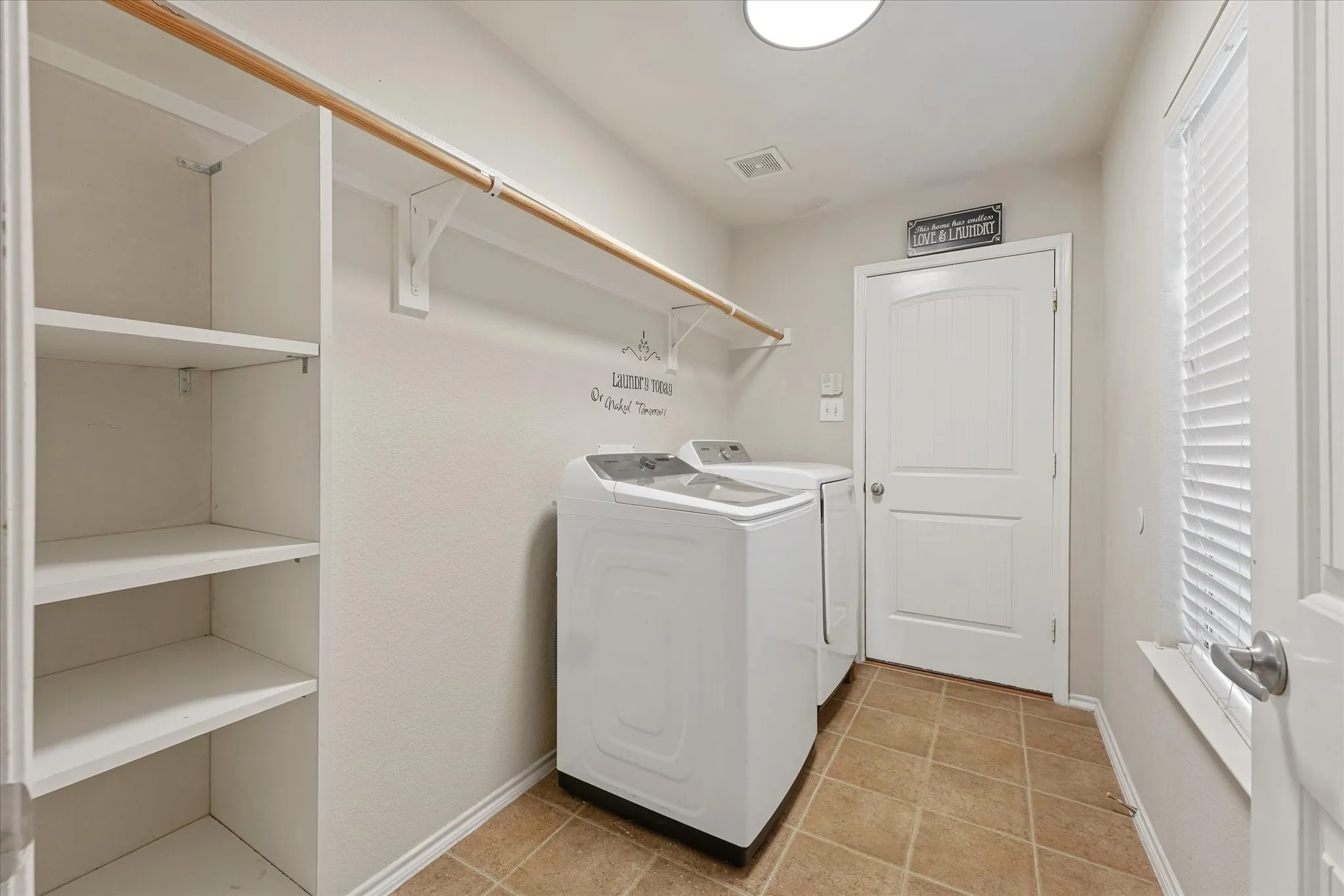 Laundry area featuring built-in shelving, a clothes rod, and tile flooring