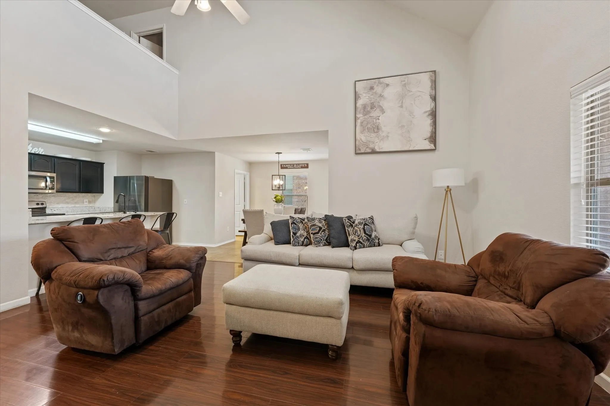 Vaulted ceiling, ceiling fan, wood-finish flooring, kitchen pass-through, and window with blinds