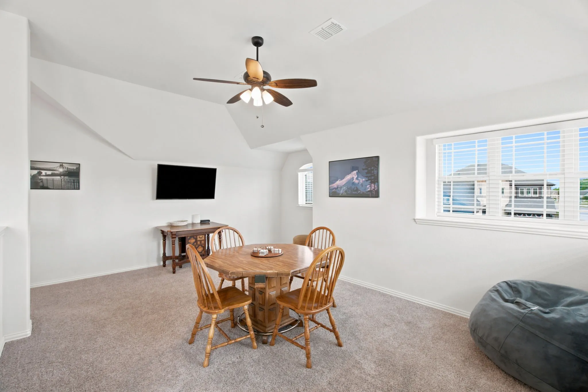 Carpeted room with a ceiling fan, sloped ceilings, and multiple windows