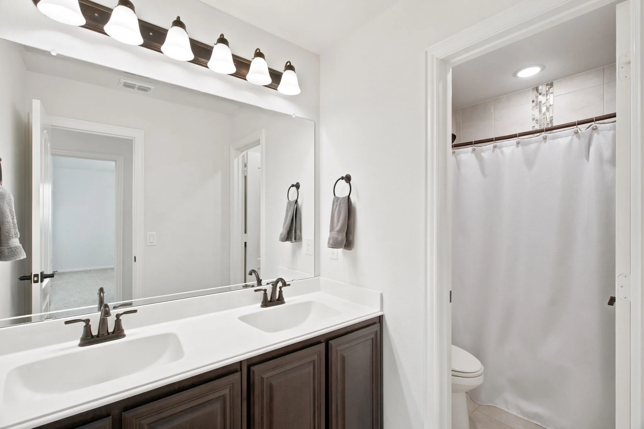Dual vanity with integrated sinks, dark wood-finish cabinetry, and oil-rubbed bronze fixtures