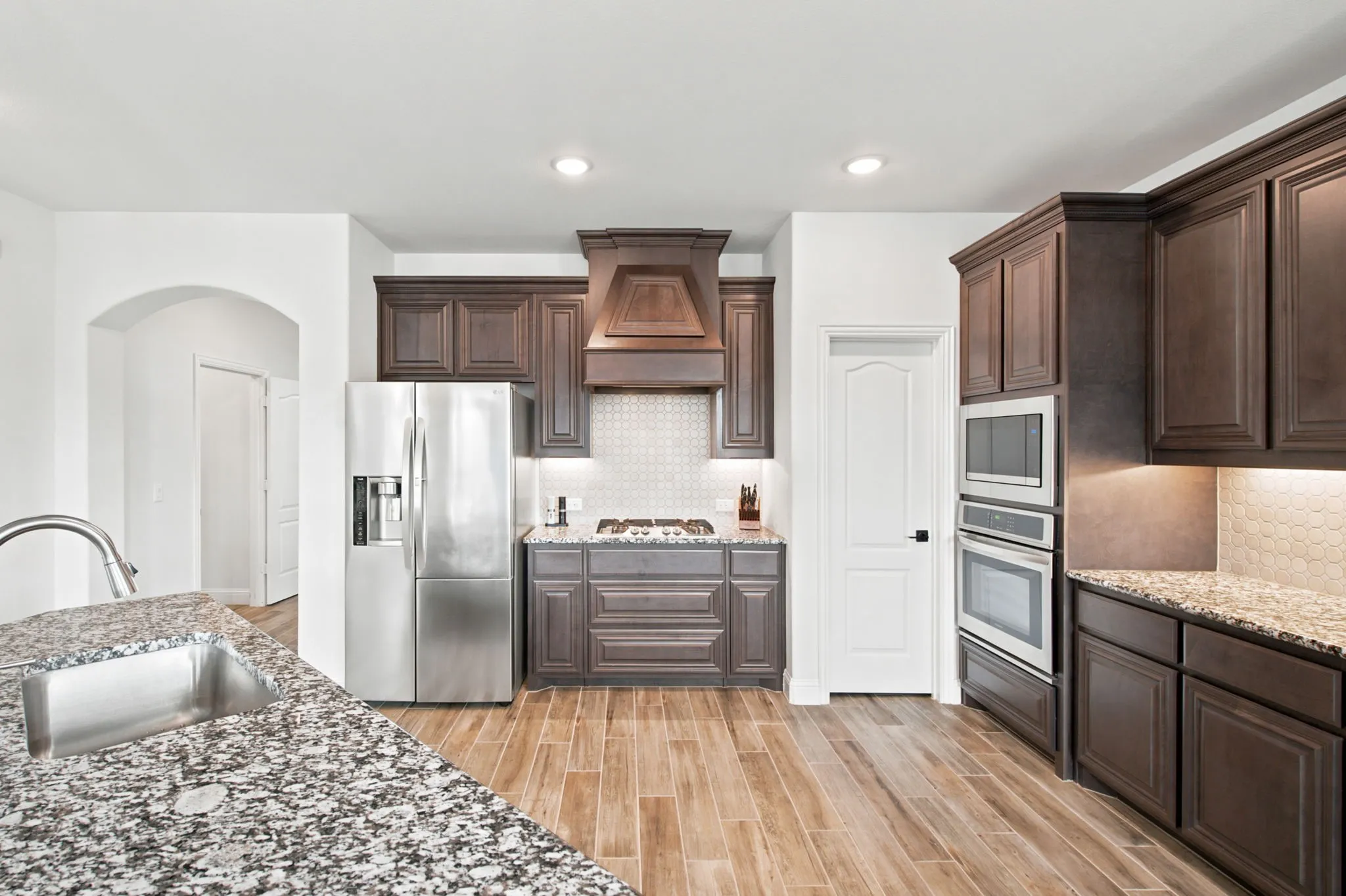 Kitchen featuring wood-look tile flooring, dark wood cabinetry, and speckled countertops