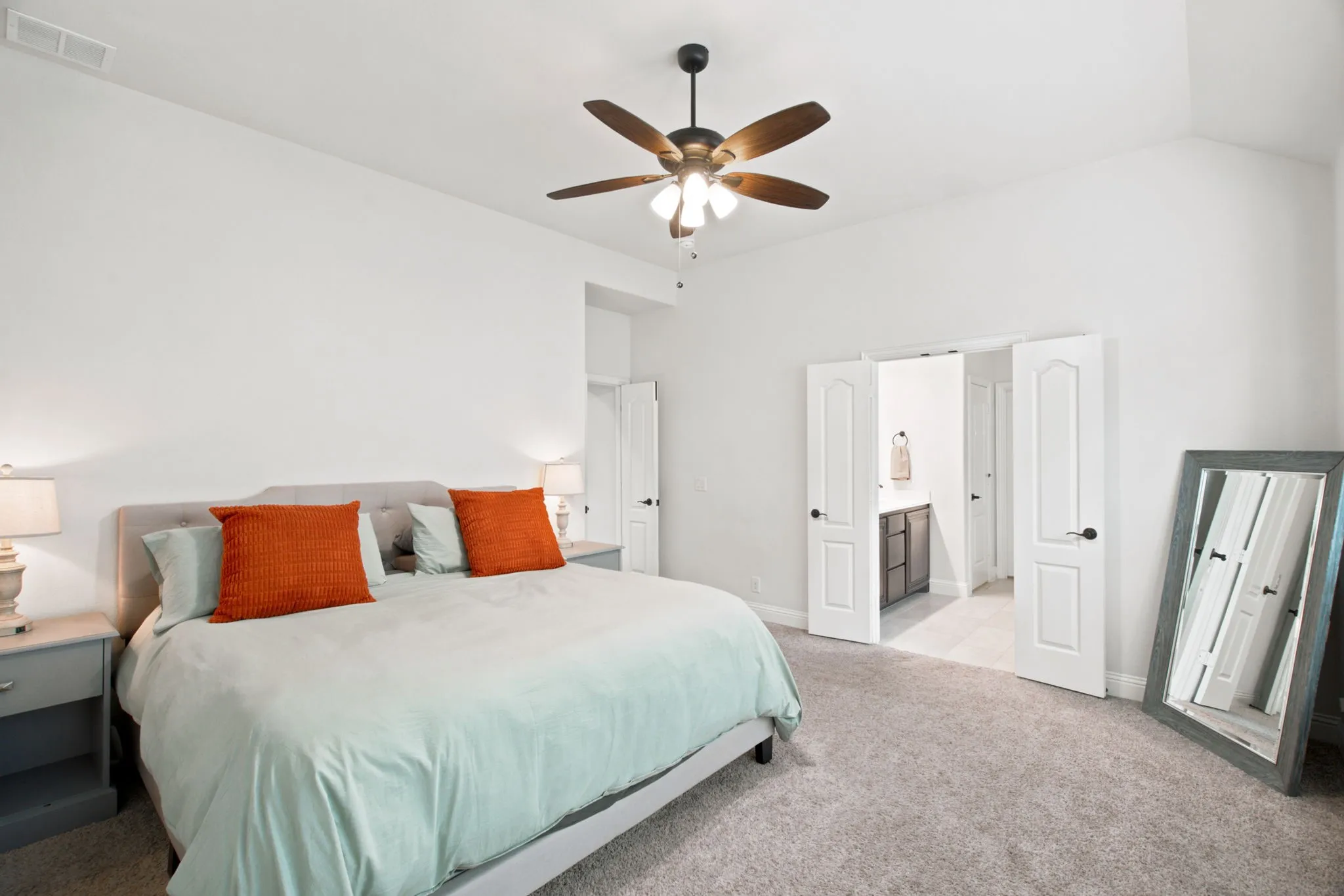 Vaulted ceiling with an attached ceiling fan, plush carpet flooring, and white paneled doors