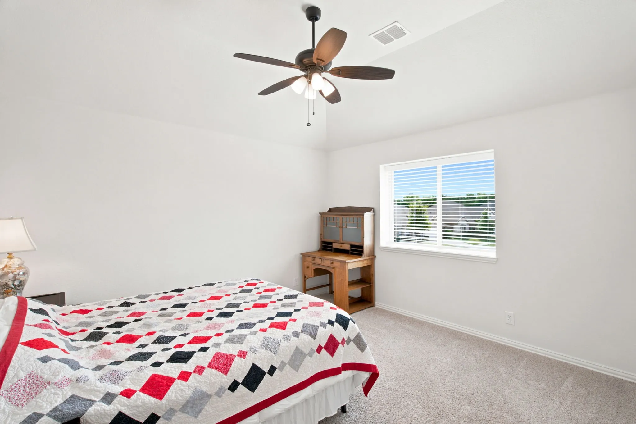 White walls, light-colored carpeting, and a ceiling fan with light fixture