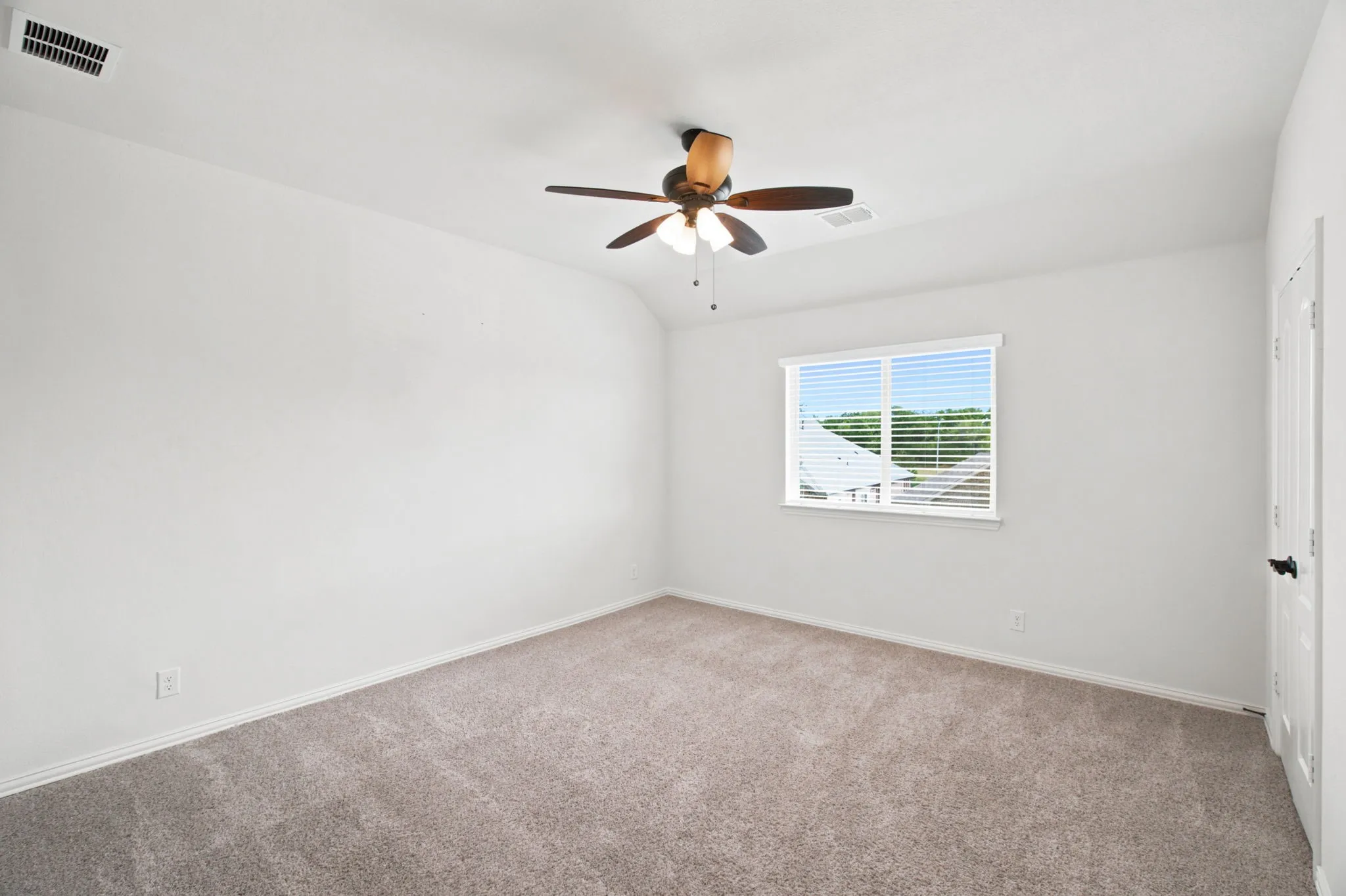 Recessed ceiling with an integrated ceiling fan and light fixture, window with blinds, and neutral carpet flooring