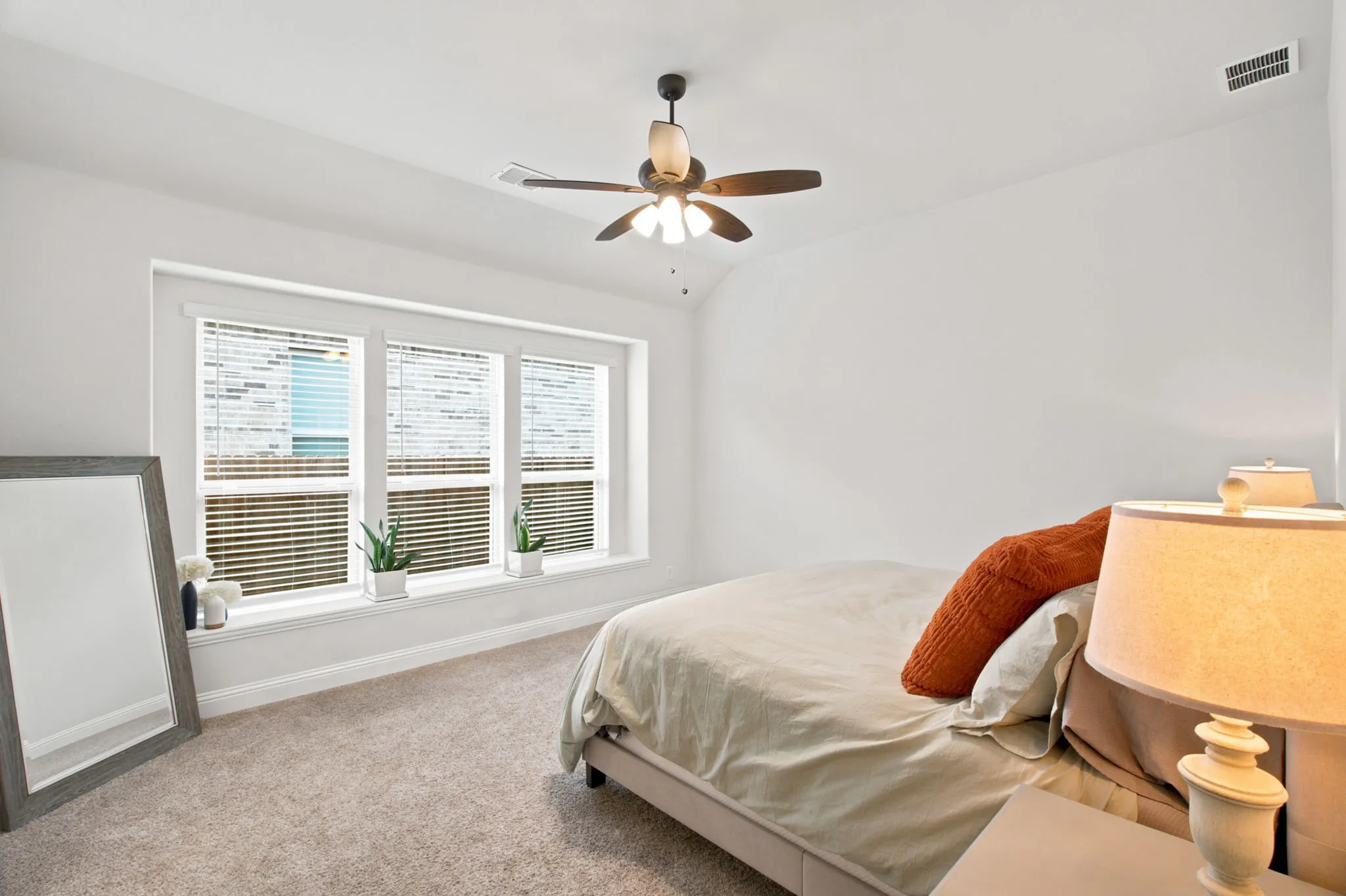 Tray ceiling, ceiling fan, triple windows, white window trim, and neutral carpeting