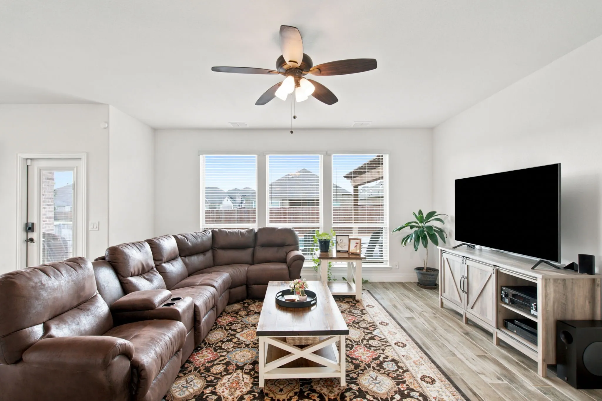 Wood-look tile flooring, white walls, and a ceiling fan with integrated lighting
