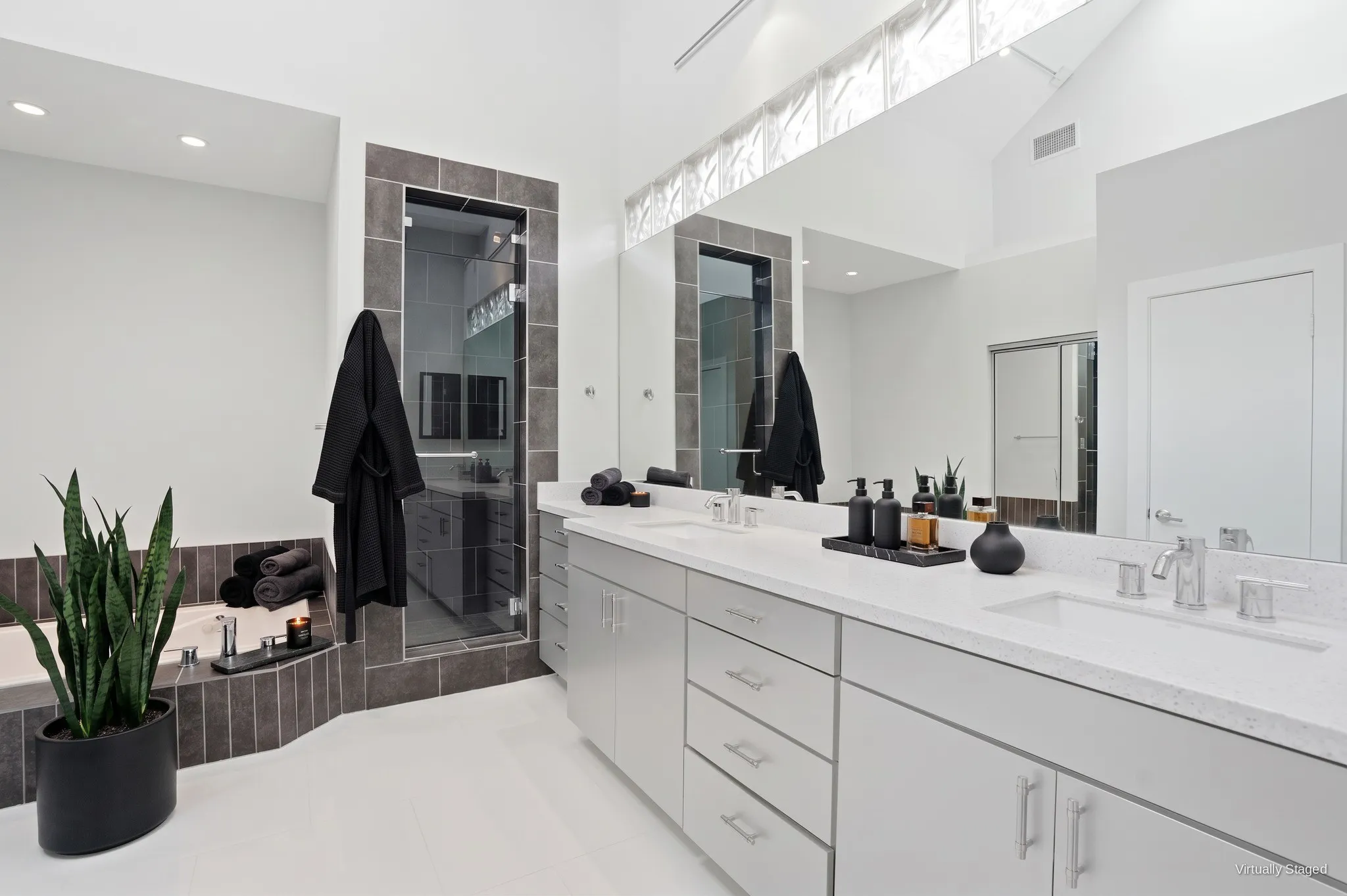 Primary bath with dual sinks, quartz countertops, an extended vanity, and glass-block clerestory windows. Virtually staged.