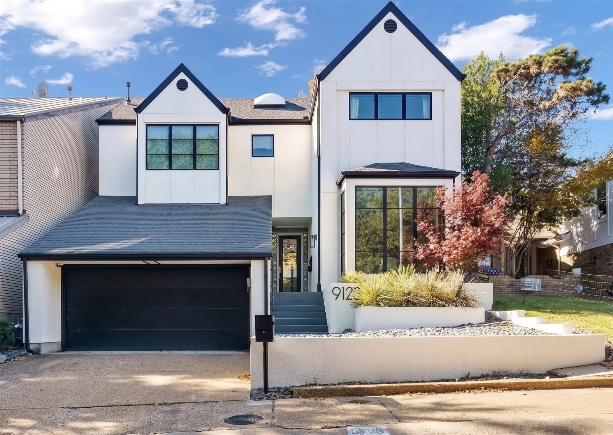 Contemporary stucco home tucked down a private drive in Dallas 75220, with black-framed windows and an attached two-car garage. Digitally enhanced.