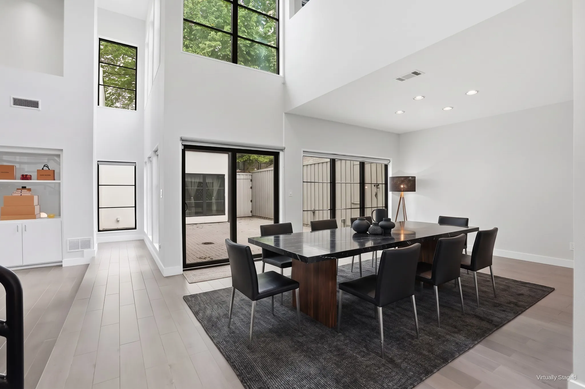 Dining area off the great room with clerestory windows and black-framed sliding glass doors that open to the courtyard. Virtually staged.