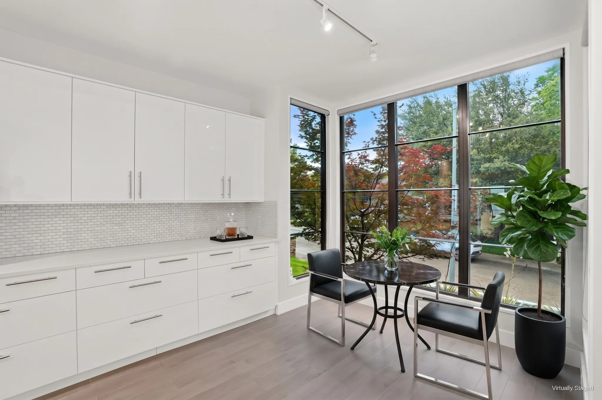 Breakfast nook wrapped in floor-to-ceiling corner windows with views of the trees. Virtually staged.