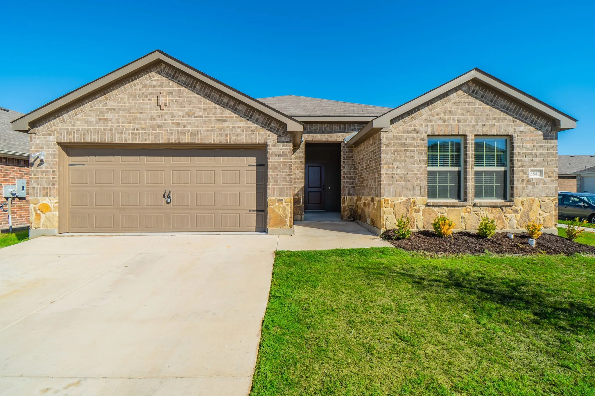 Brick exterior with stone accents, an attached two-car garage, and a concrete driveway