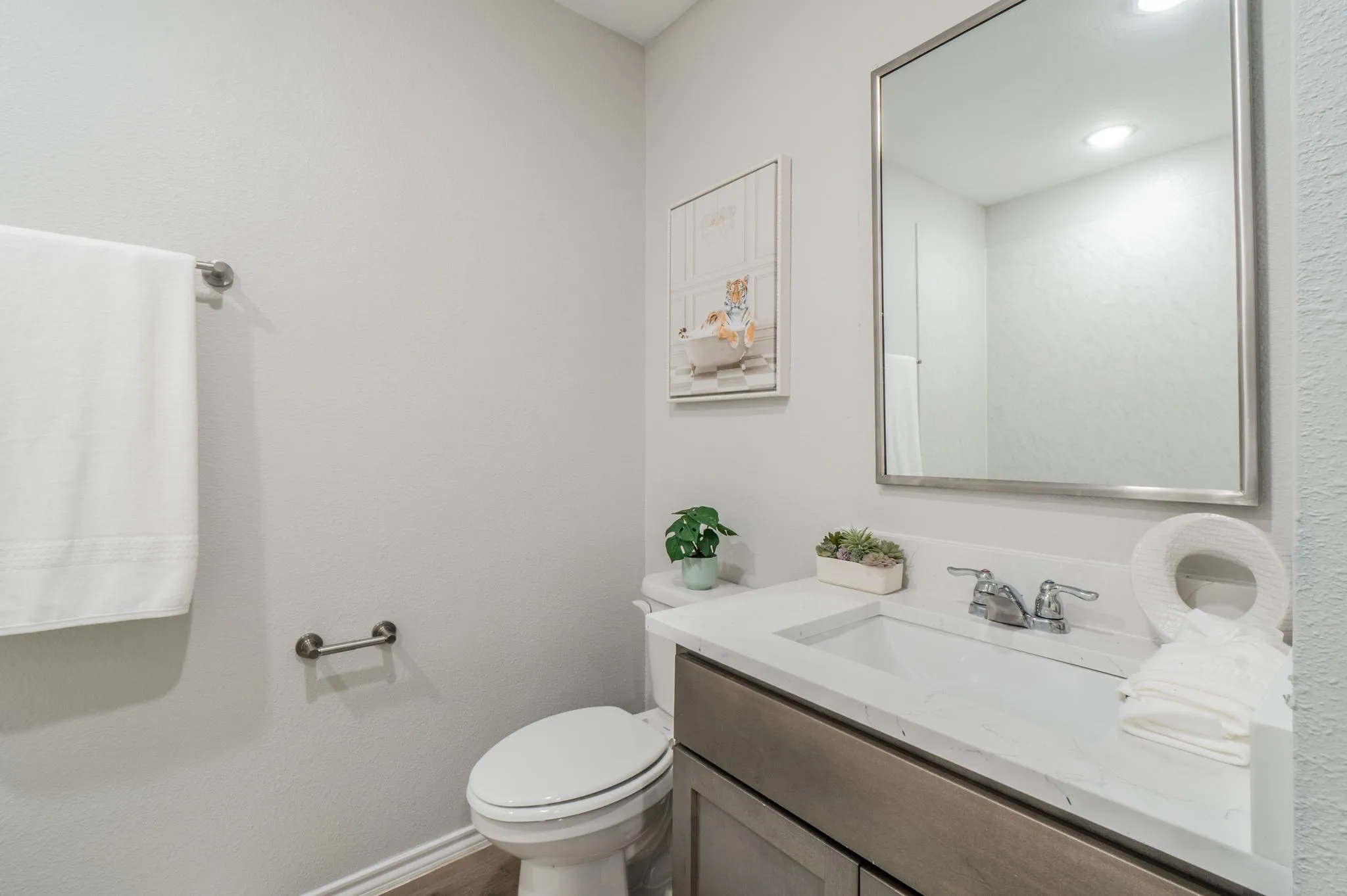 Vanity with a rectangular undermount sink, dual-handle faucet, and reflective framed mirror