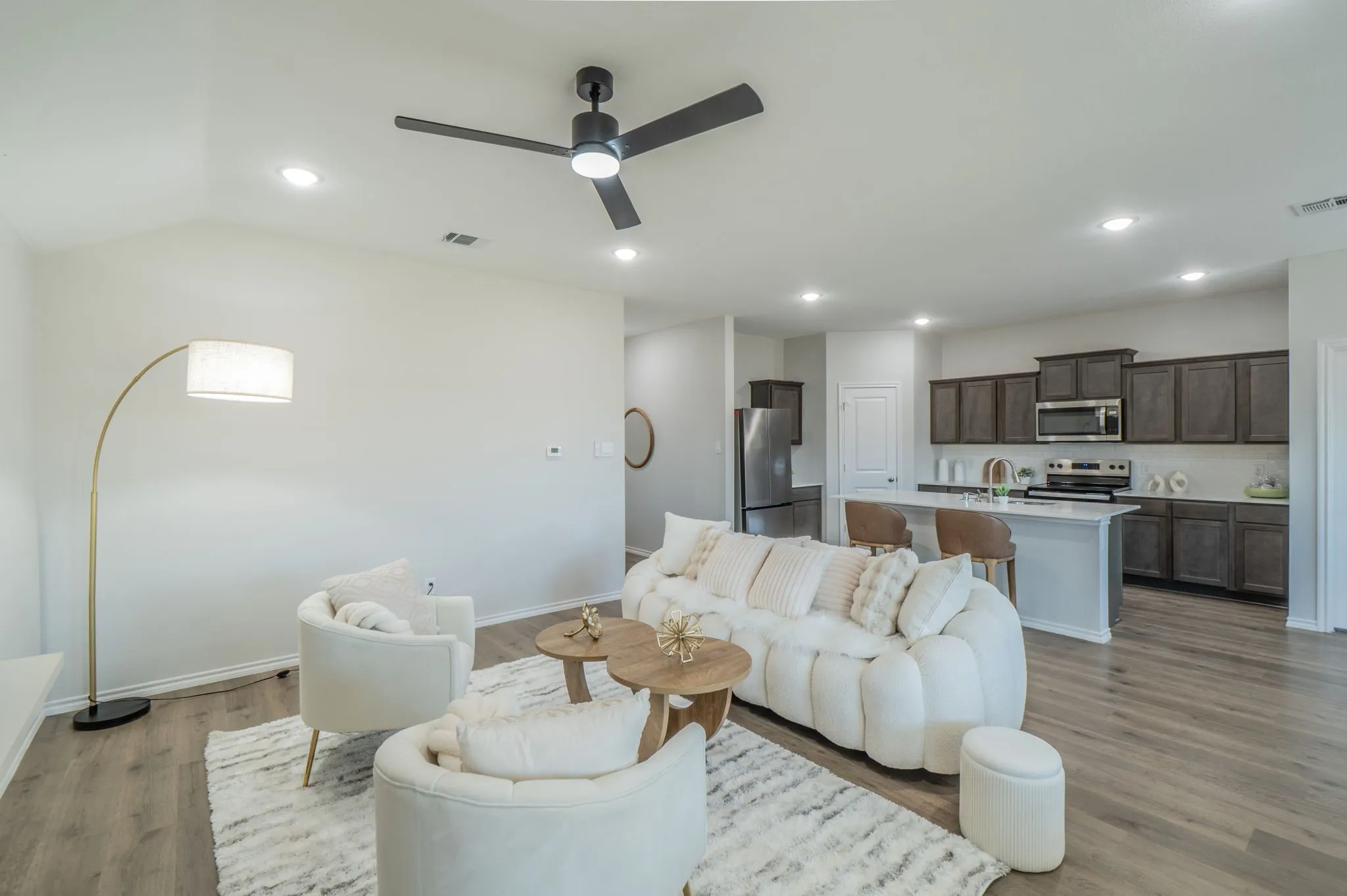 Wood-finish flooring throughout, recessed lighting, ceiling fan, and kitchen featuring dark cabinetry, stainless steel appliances, and a central island