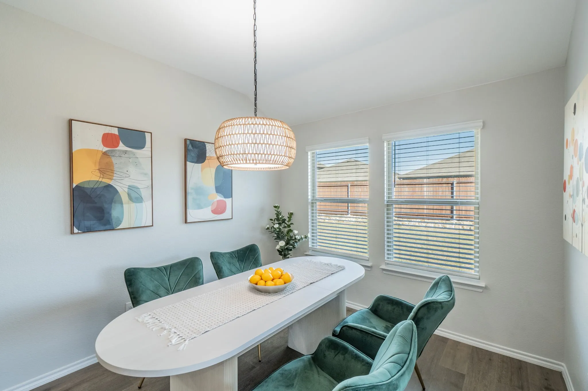 Two windows with horizontal blinds, wood-finish flooring, and a woven pendant light fixture