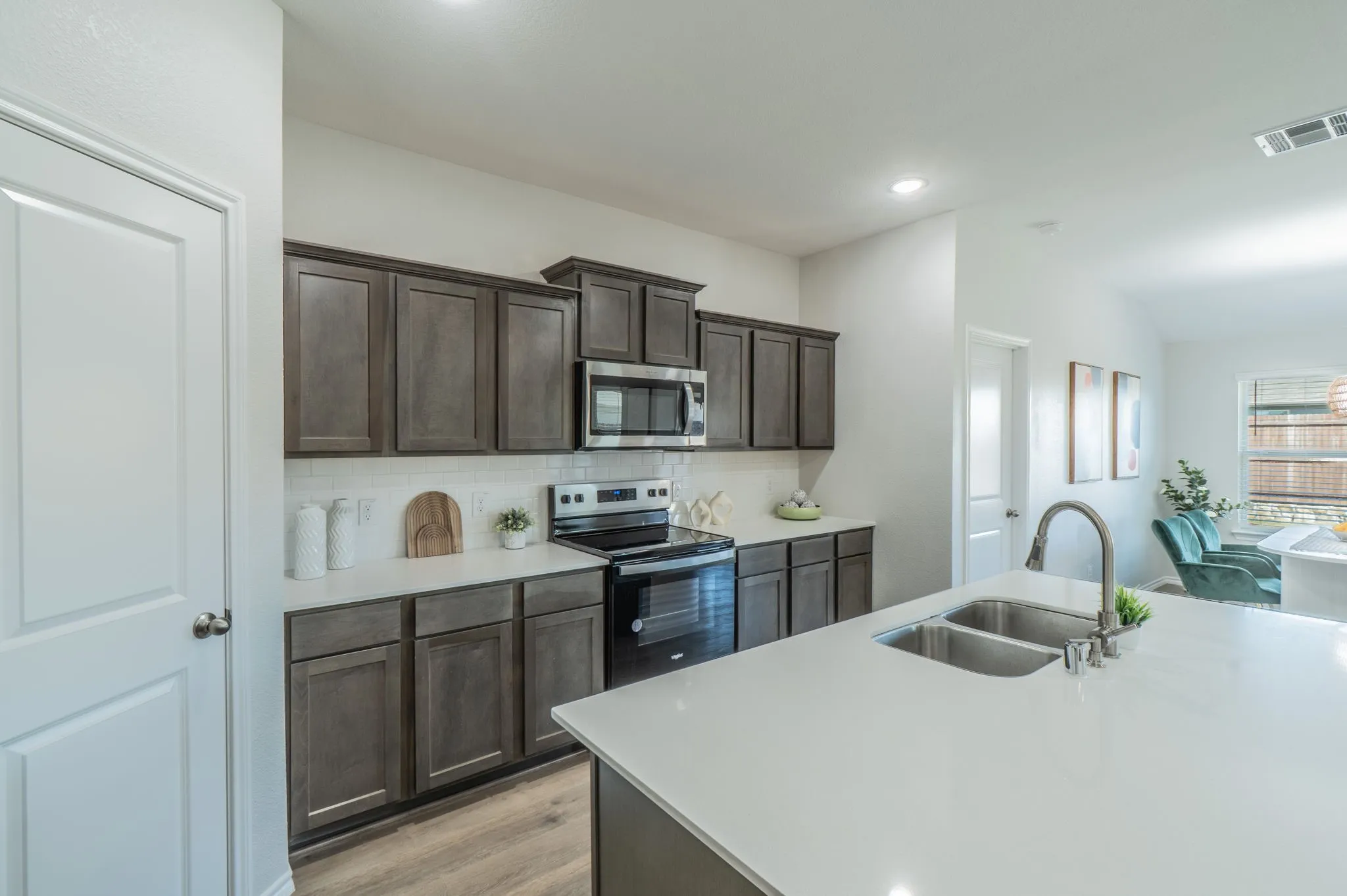 Kitchen featuring dark wood-finish cabinetry, white subway tile backsplash, white countertops, and stainless steel appliances