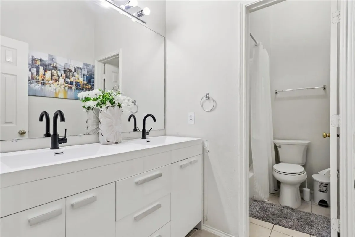 Dual vanity with integrated sinks, matte black faucets, and a full-width mirror