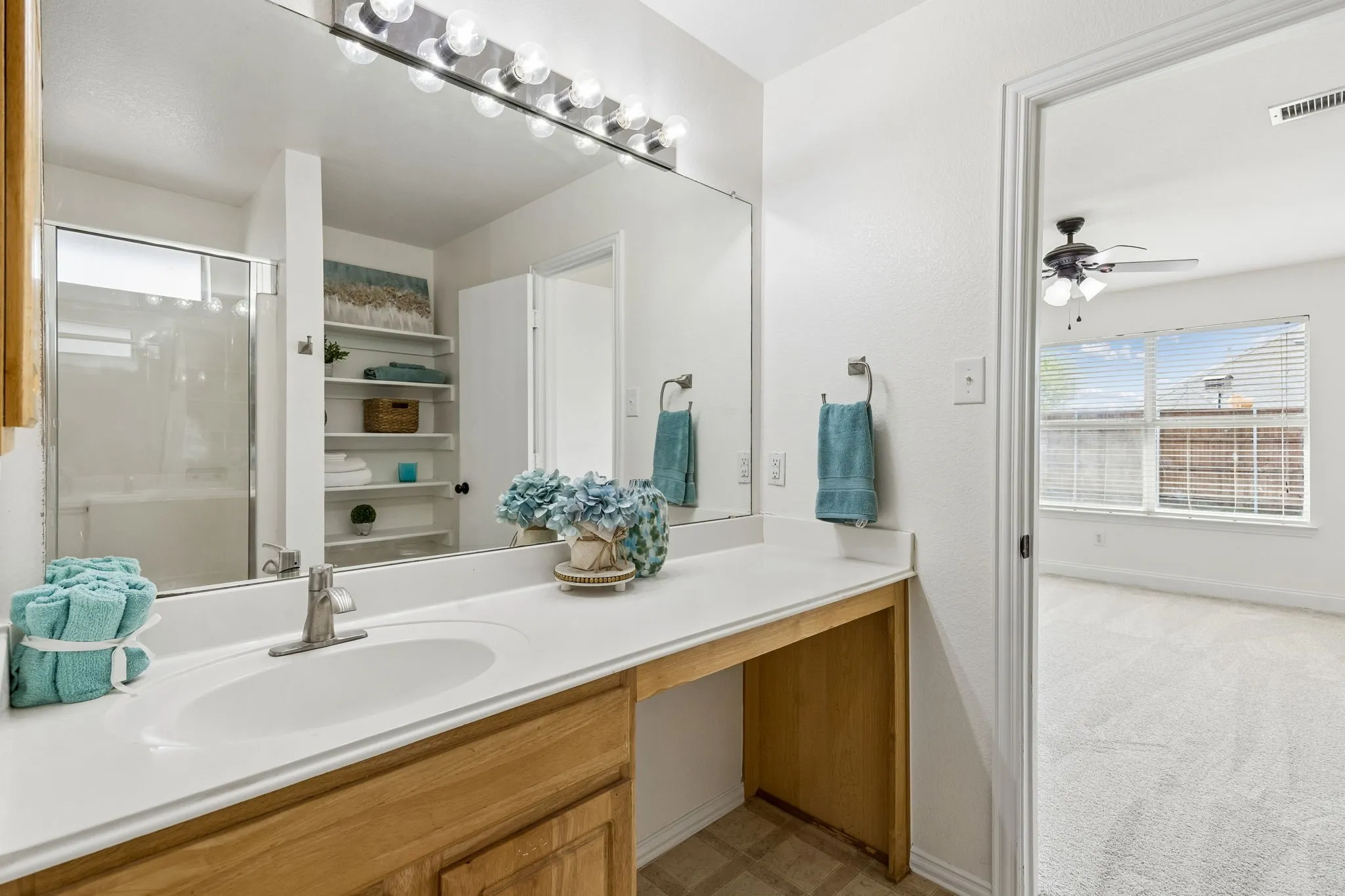 Primary bathroom with extended vanity, storage, and bright finishes.