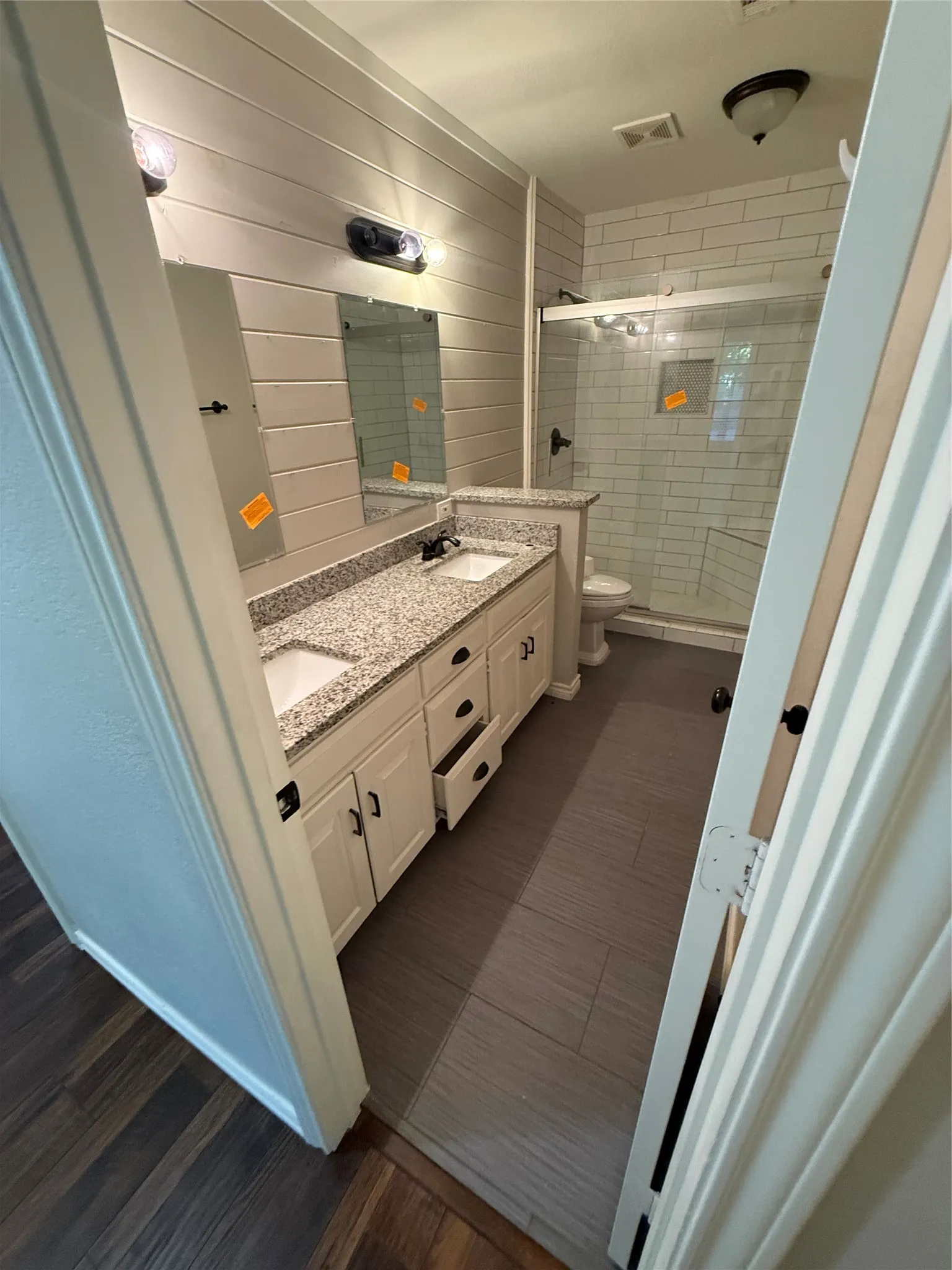 Dual vanity with granite-style countertop and integrated sinks, complemented by shiplap wall paneling and rectangular mirrors