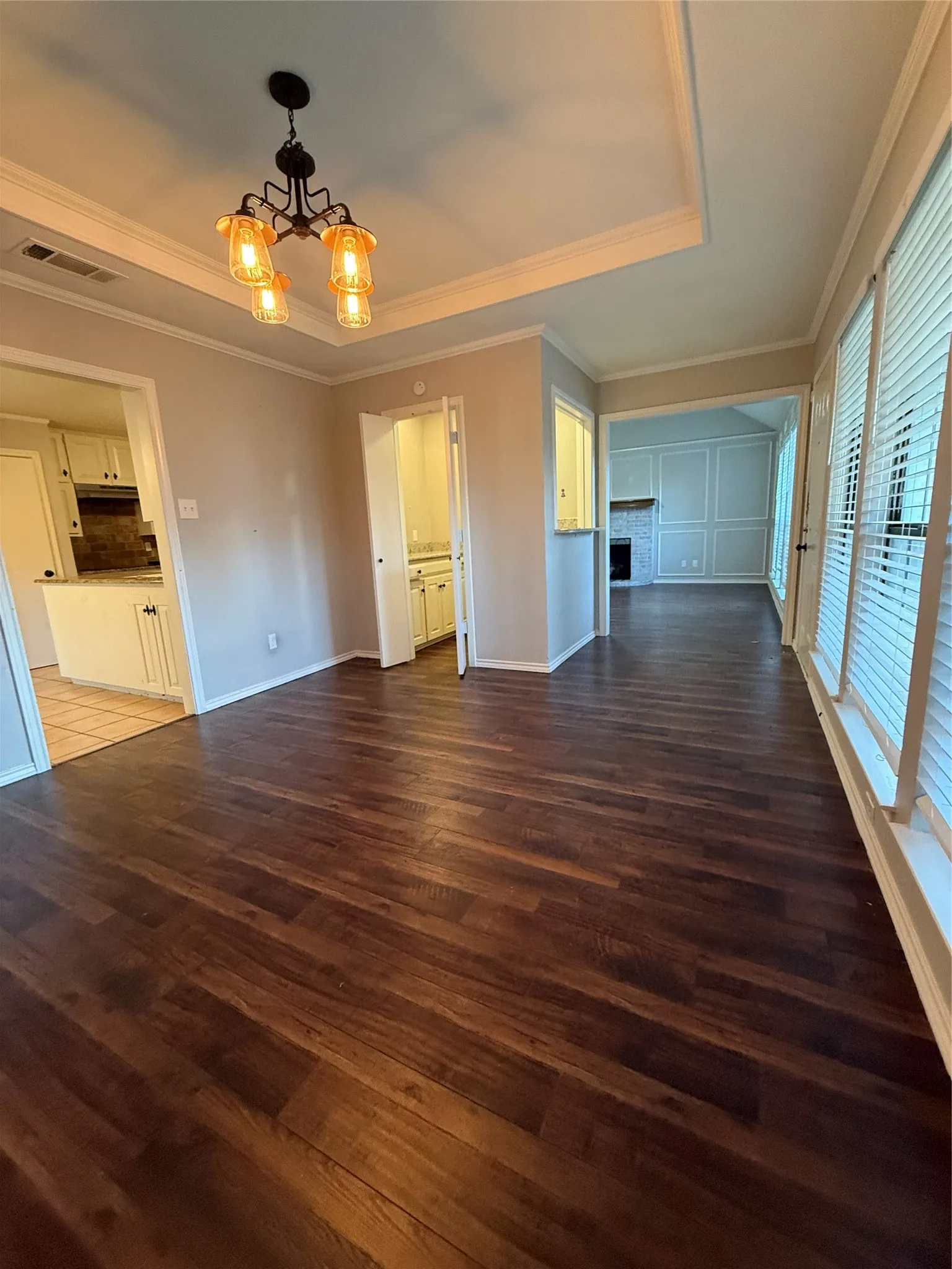 Wood-finish flooring throughout, featuring a tray ceiling with a decorative chandelier