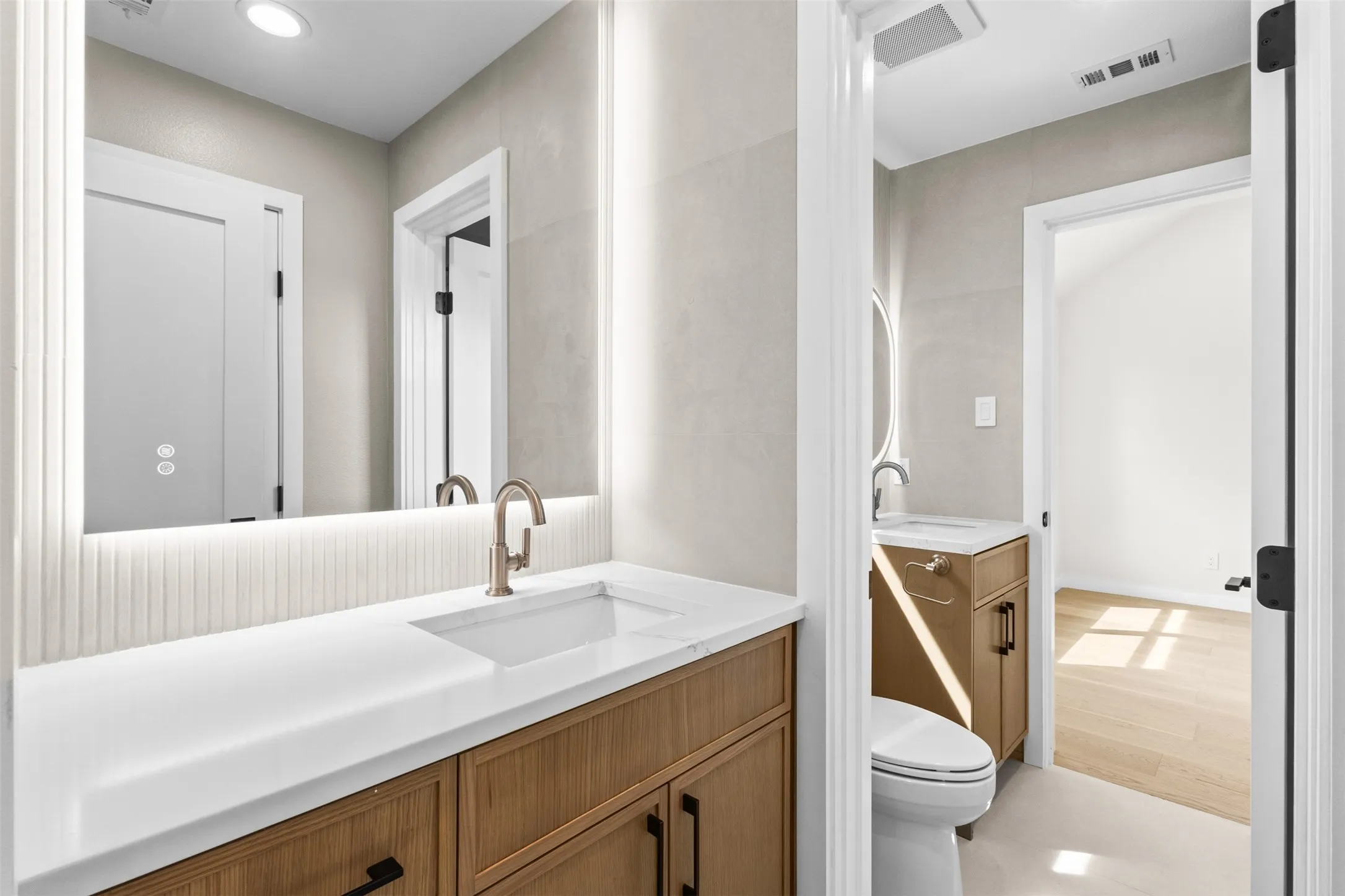 Double vanity design with integrated sinks, wood-finish cabinetry, and contemporary wall-mounted mirrors