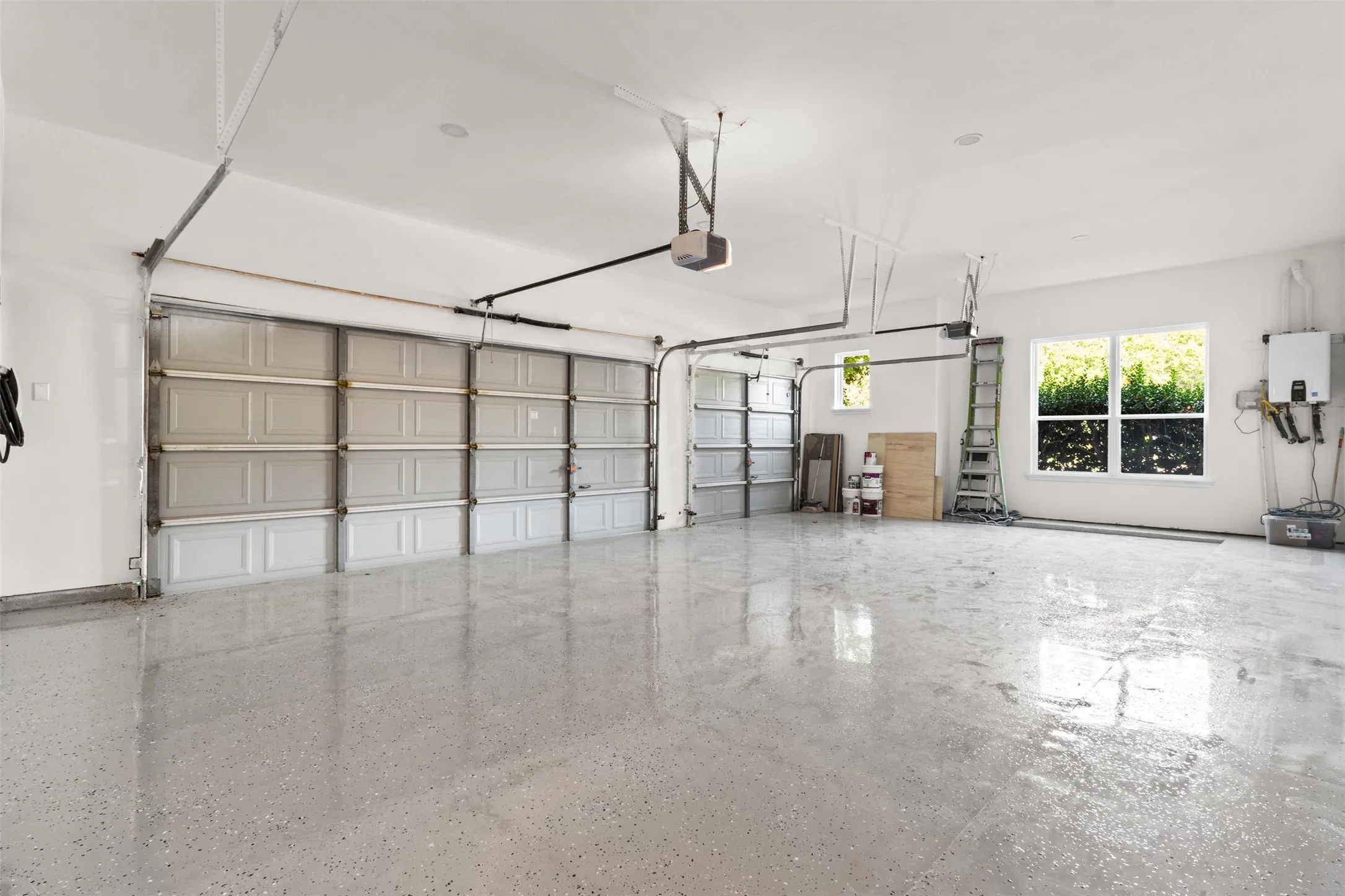 Spacious garage featuring two overhead doors, recessed lighting, and a durable speckled floor finish