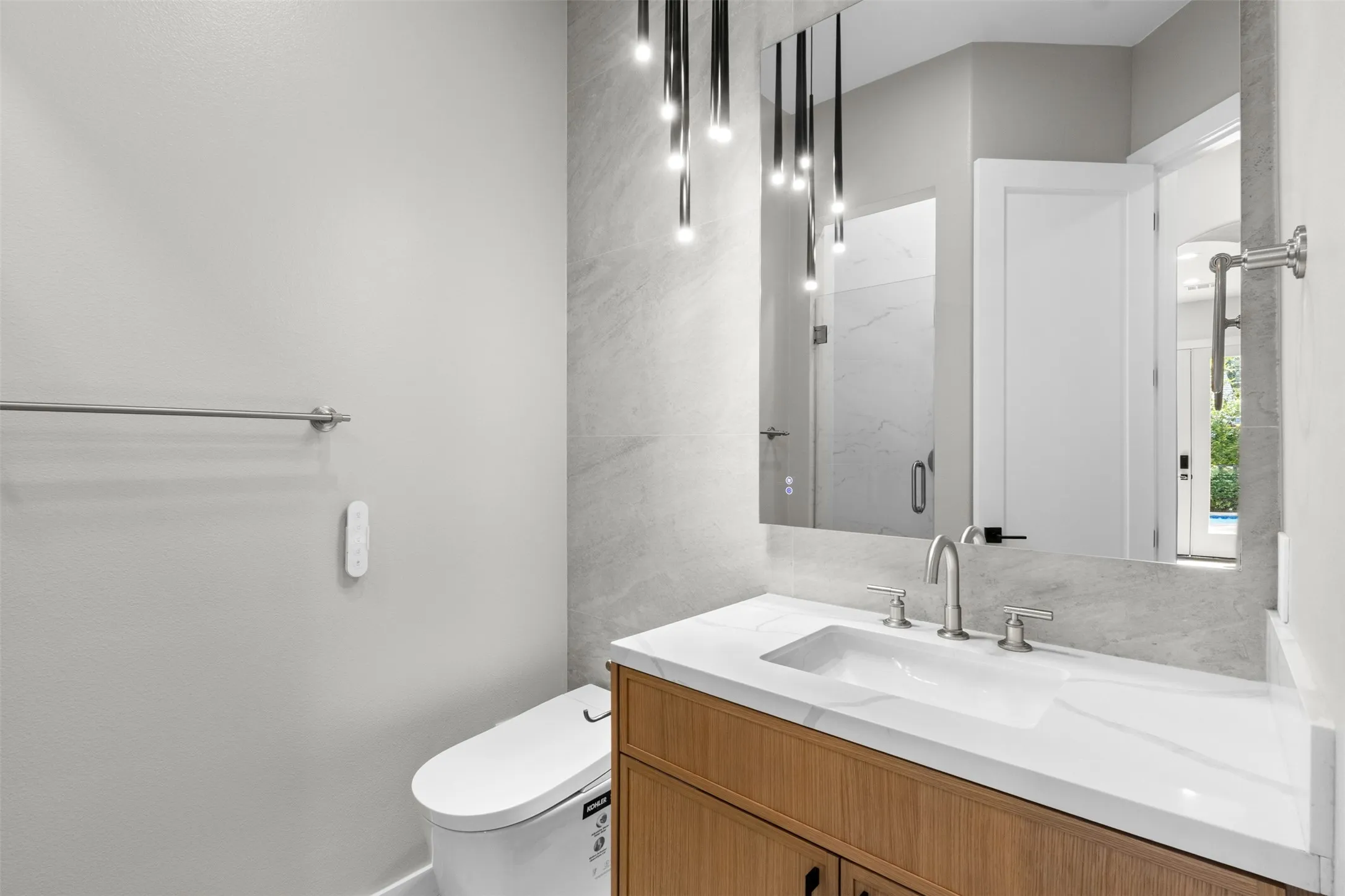 Modern vanity with an integrated rectangular sink, wood-finish cabinetry, contemporary wall-mounted lighting, and a full-width mirror
