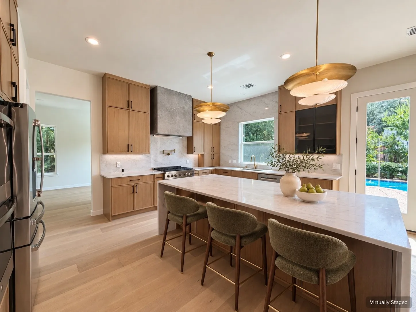 Gourmet kitchen with light wood-finish cabinetry, a large center island with a light-toned countertop, and a full suite of stainless steel appliances