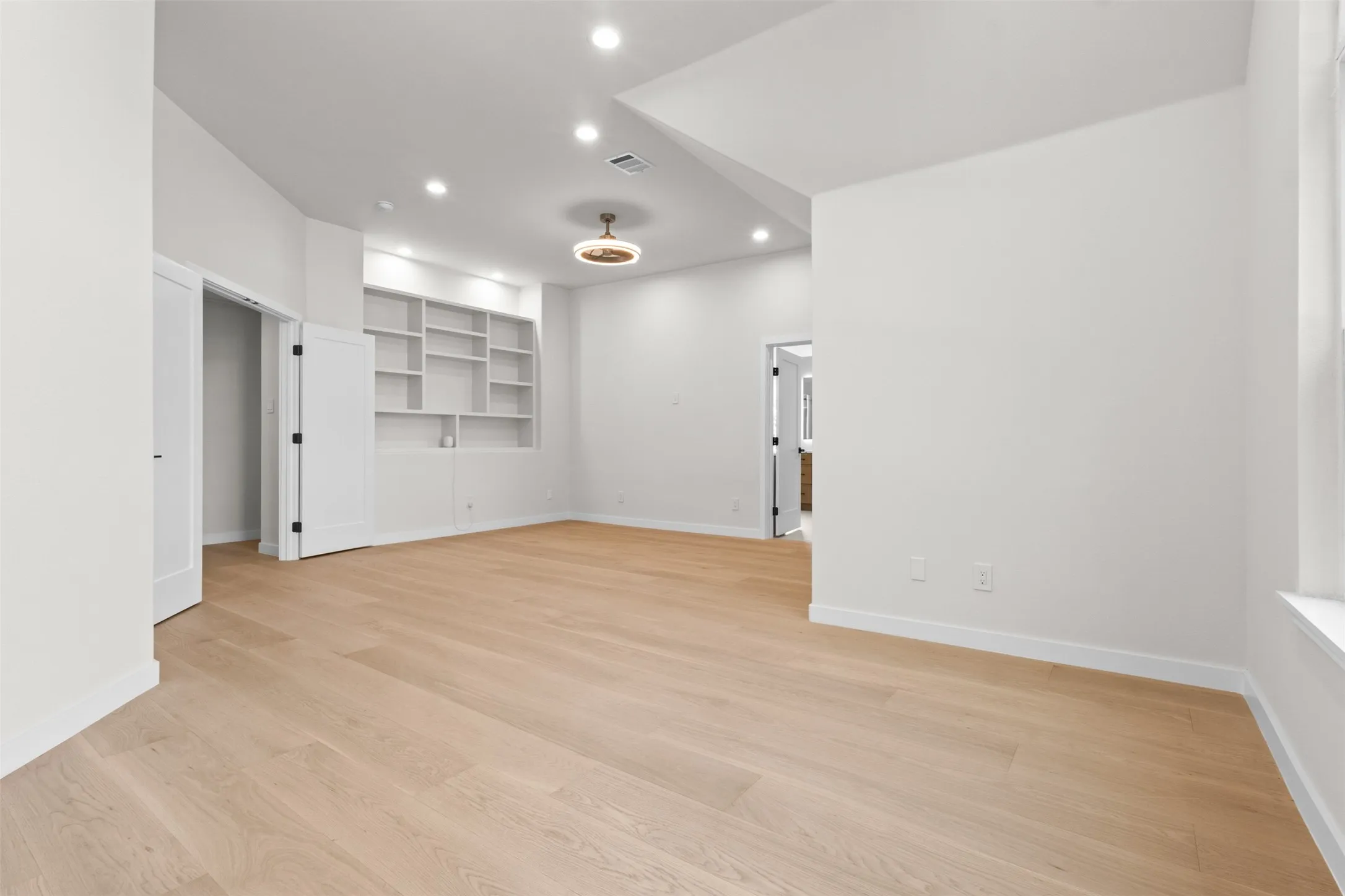 Light wood-finish flooring, recessed lighting, and built-in shelving