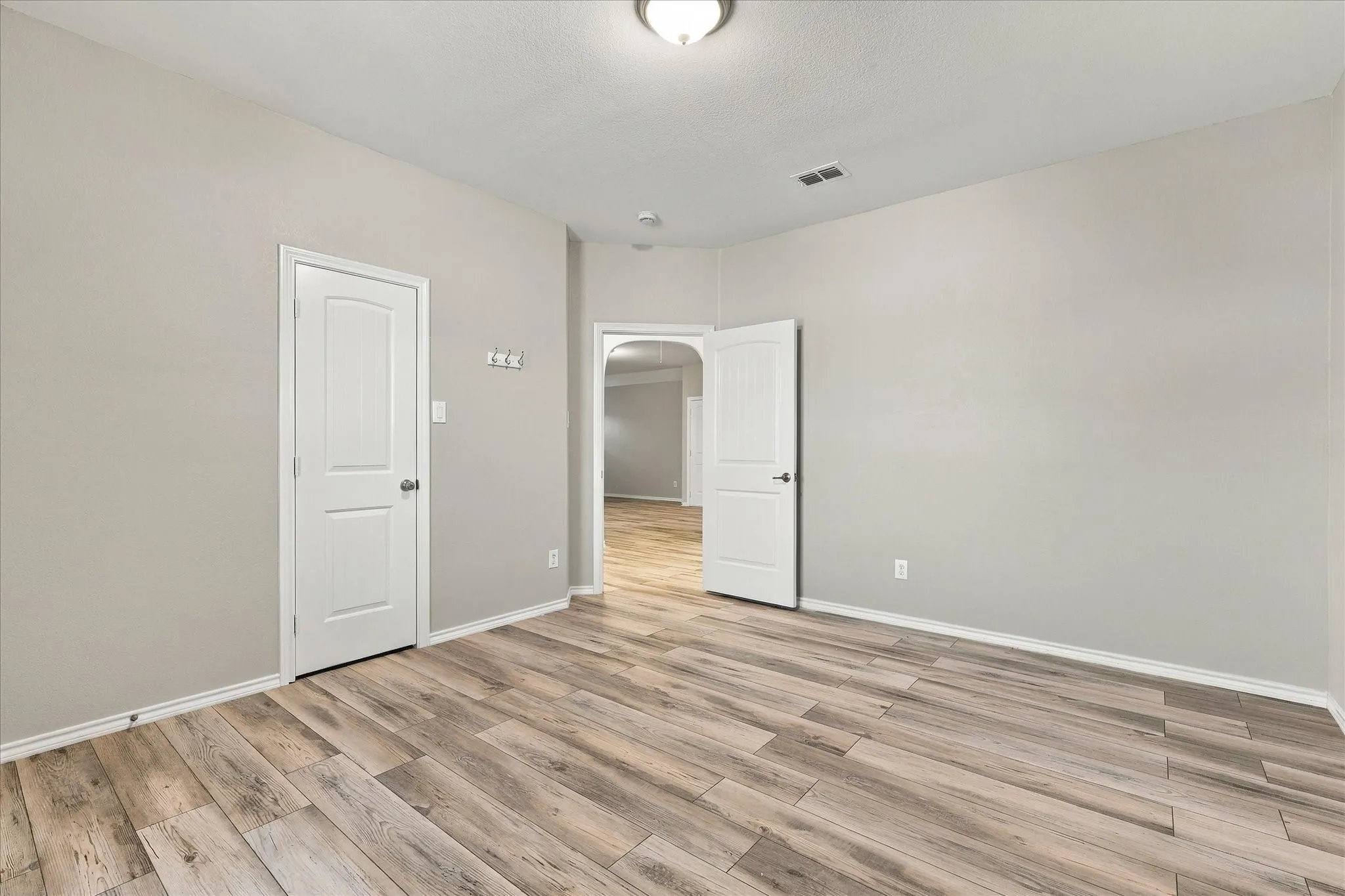 Neutral wall color, wood-finish flooring, white paneled doors, ceiling-mounted light fixture, recessed lighting