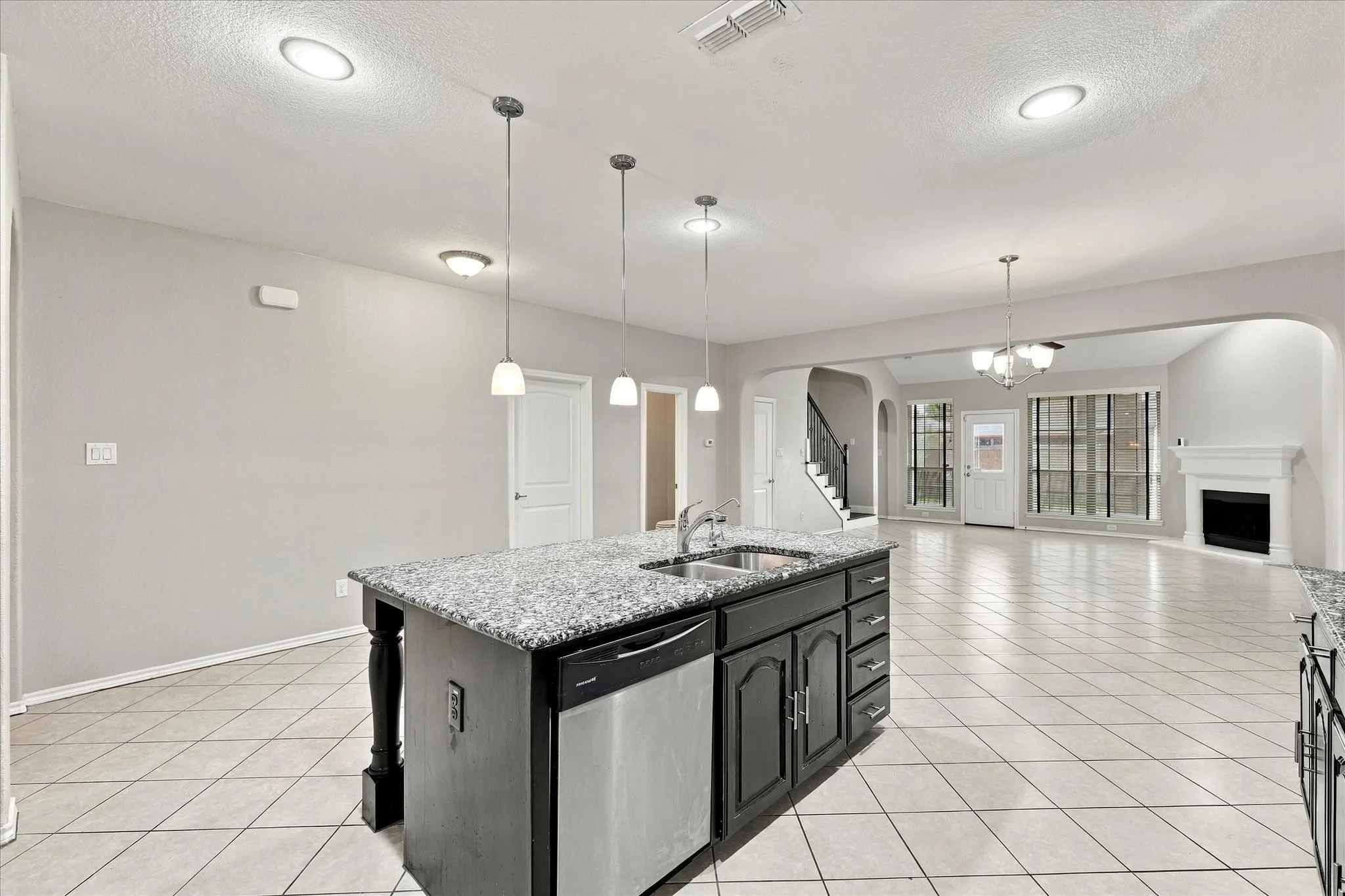 Kitchen island featuring a double-basin sink, stainless steel dishwasher, and pendant lighting