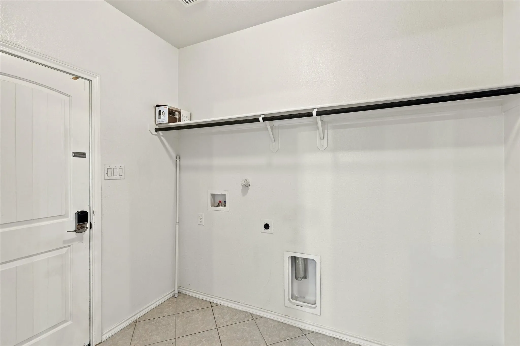 Utility area featuring a built-in hanging rod, overhead shelving, and neutral tile flooring