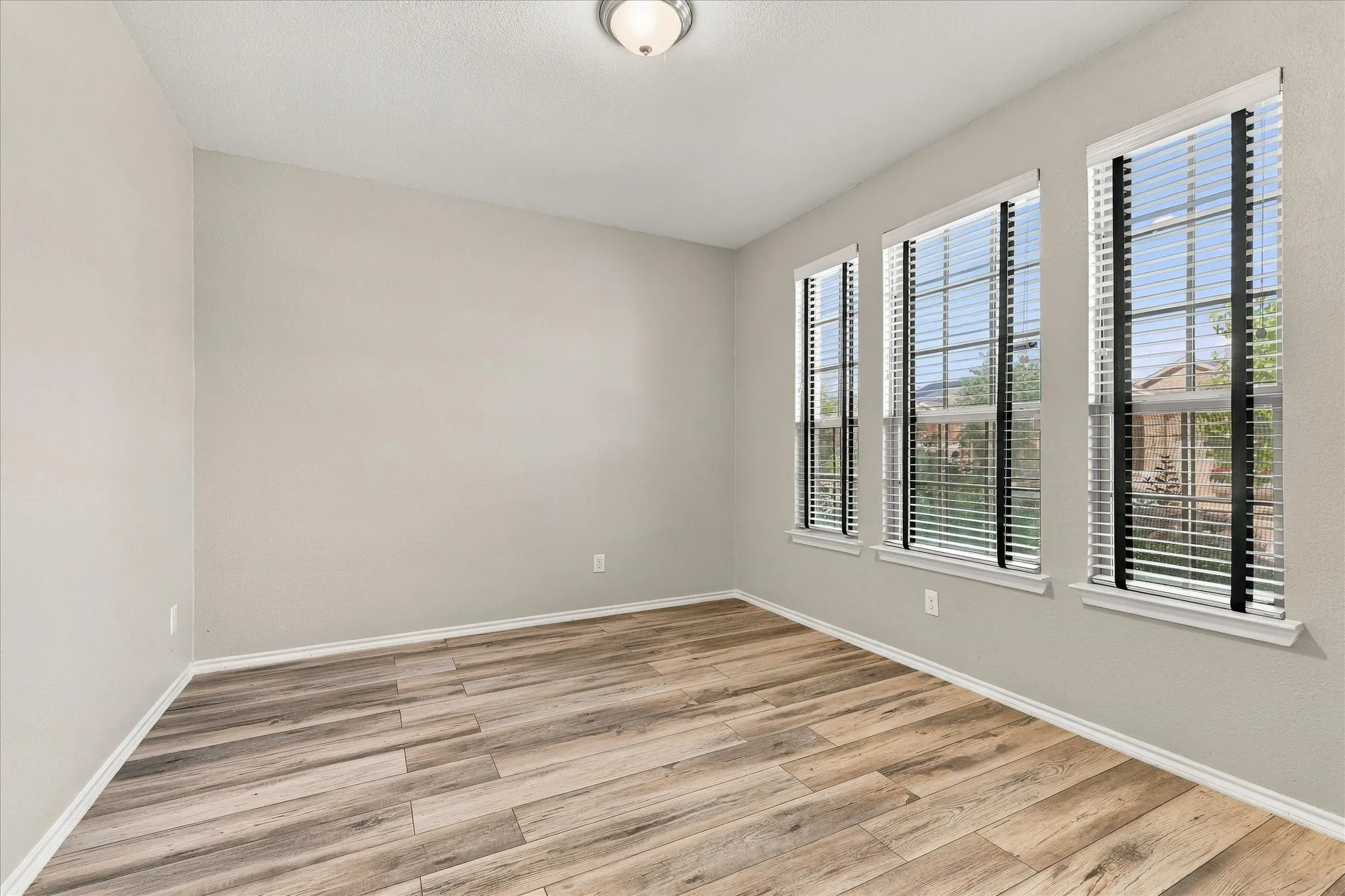 Neutral wall paint, wood-finish flooring, and multiple windows with blinds