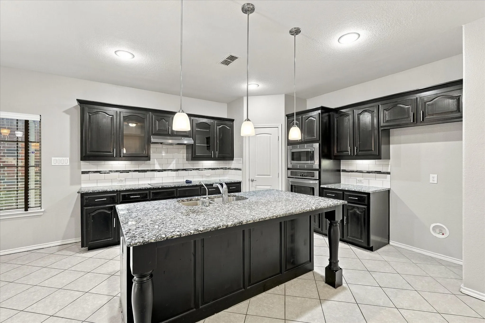 Central island with a granite countertop and undermount sink