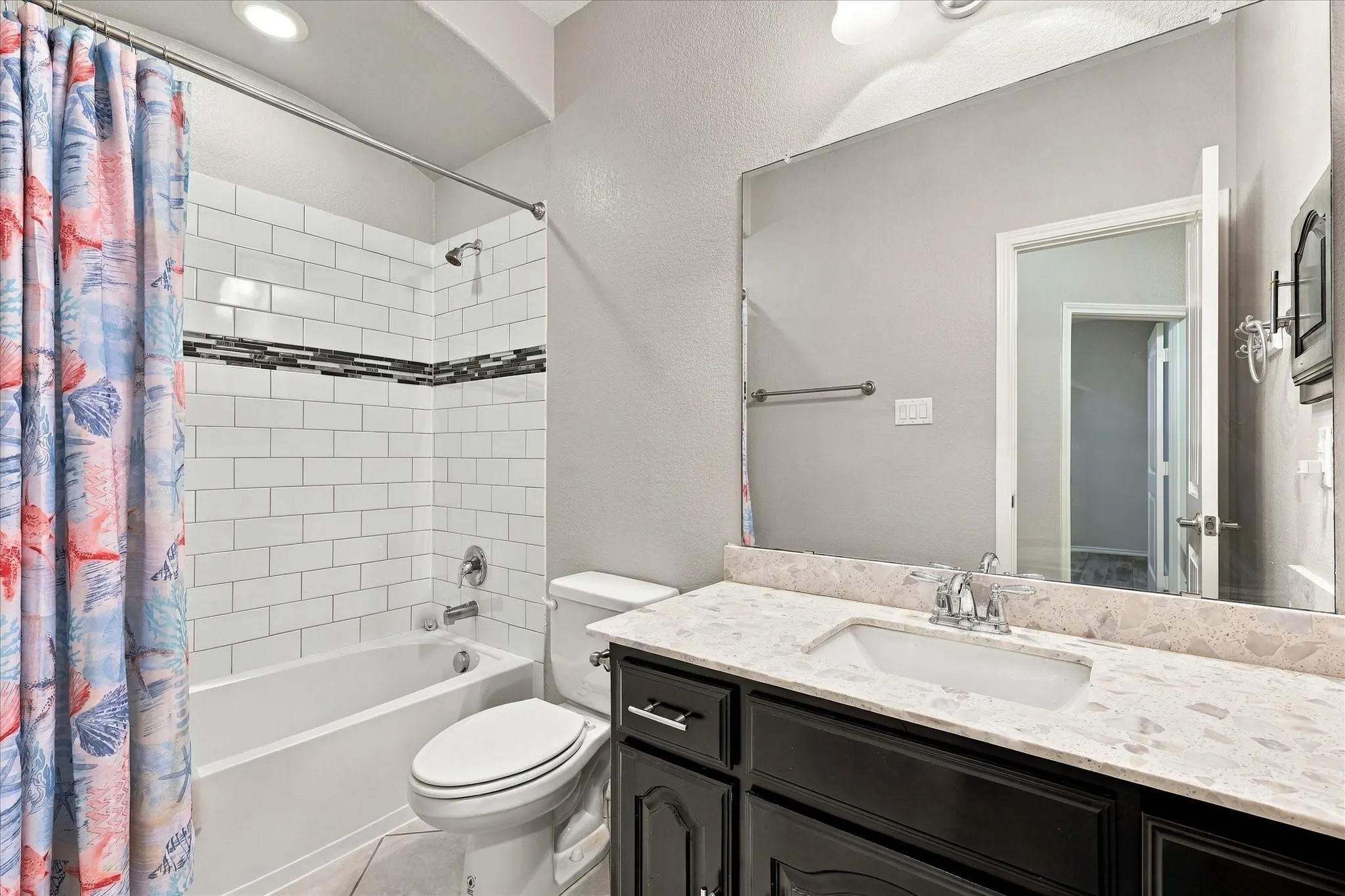 Bathroom featuring a single vanity with stone-finish countertop, undermount sink, and dark wood-finish cabinetry