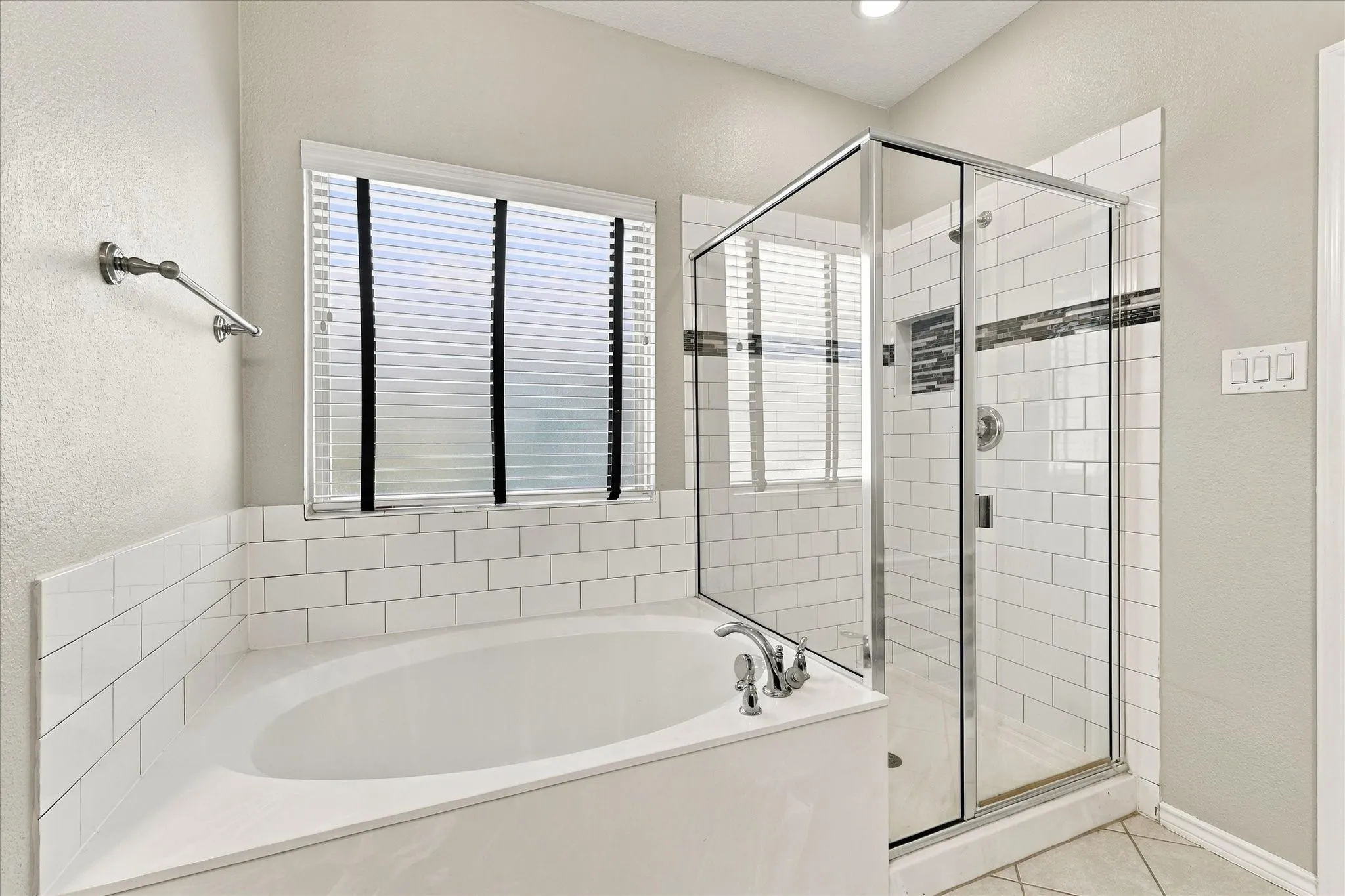 Built-in soaking tub with subway tile surround, glass-enclosed shower with subway tile, and tile flooring
