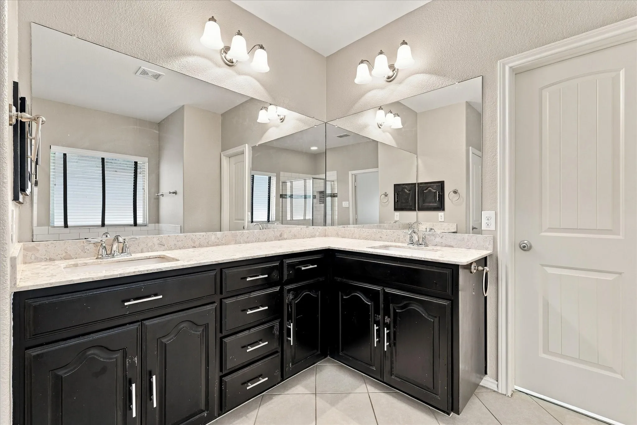 Dual vanity with stone-look countertops, dark wood-finish cabinetry, and brushed nickel hardware