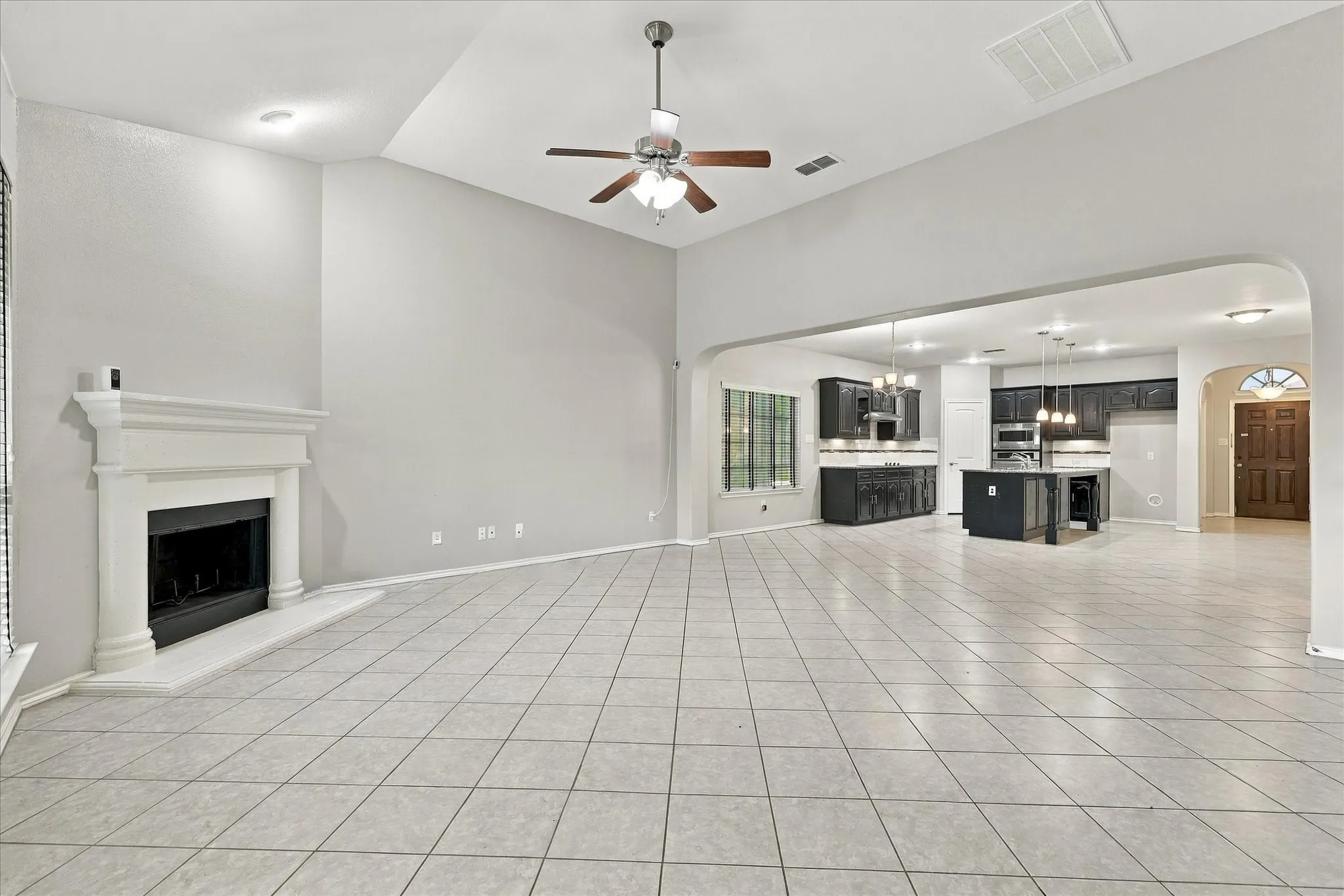 Spacious room featuring vaulted ceilings, a built-in fireplace with a mantel, and tiled flooring